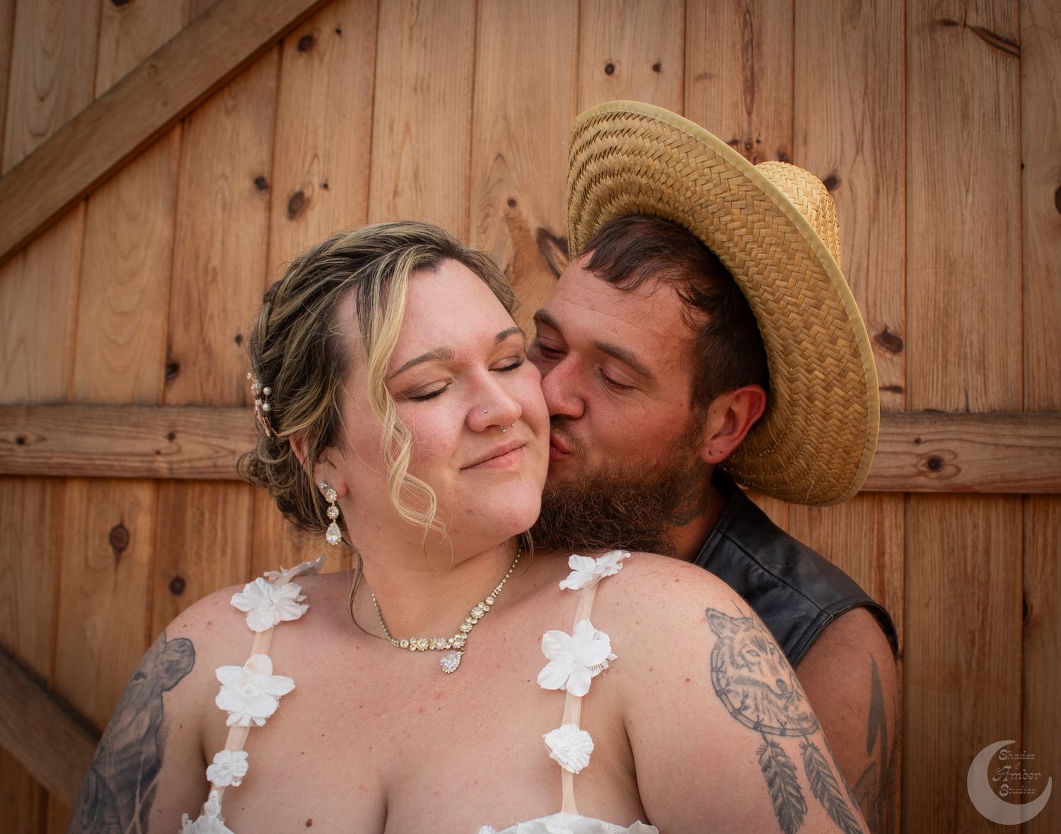 A tender moment between newlyweds against a rustic wooden barn backdrop.