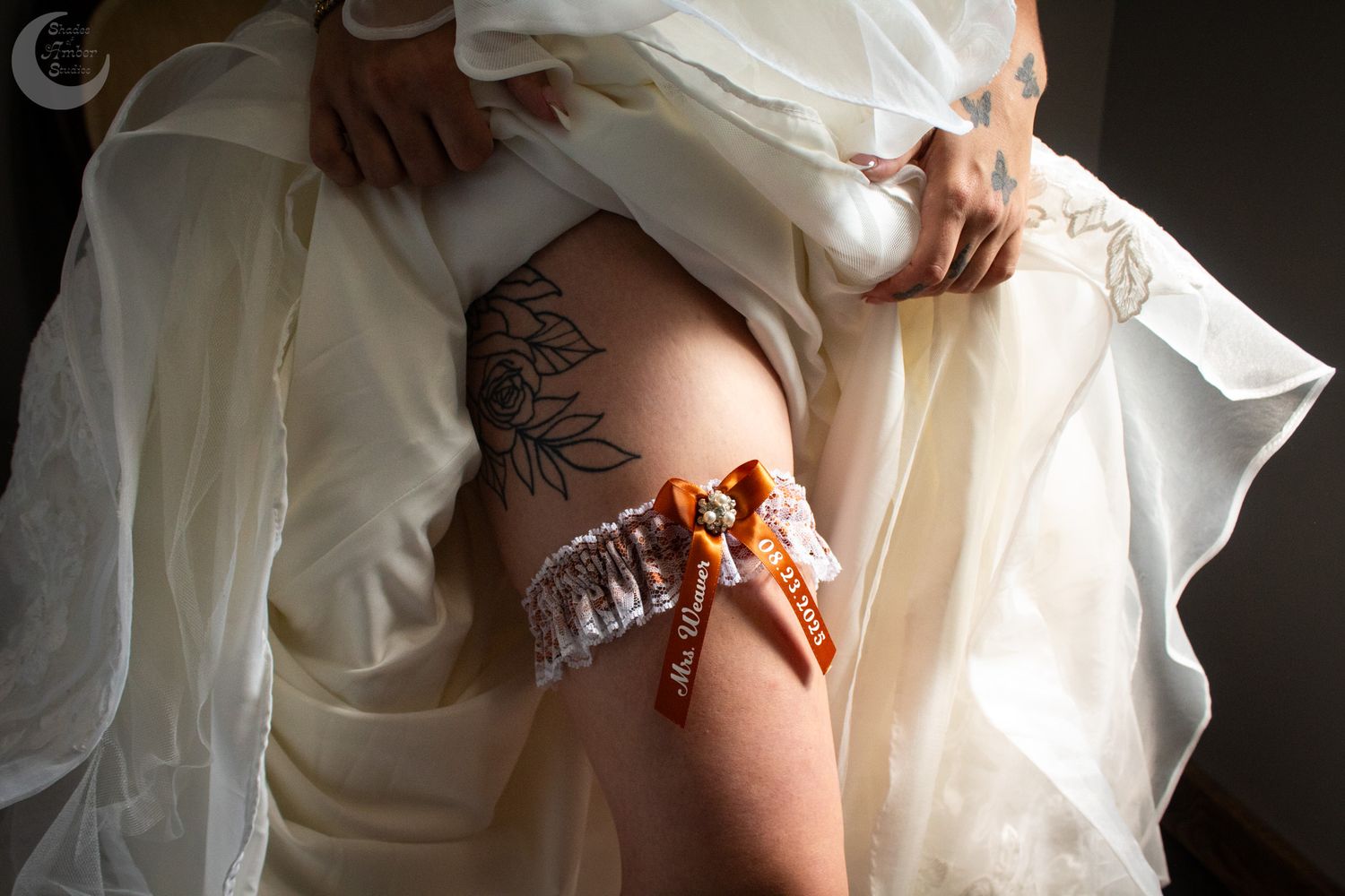 A detailed look at white lace detailing on a wedding dress as it drapes across someone's body.