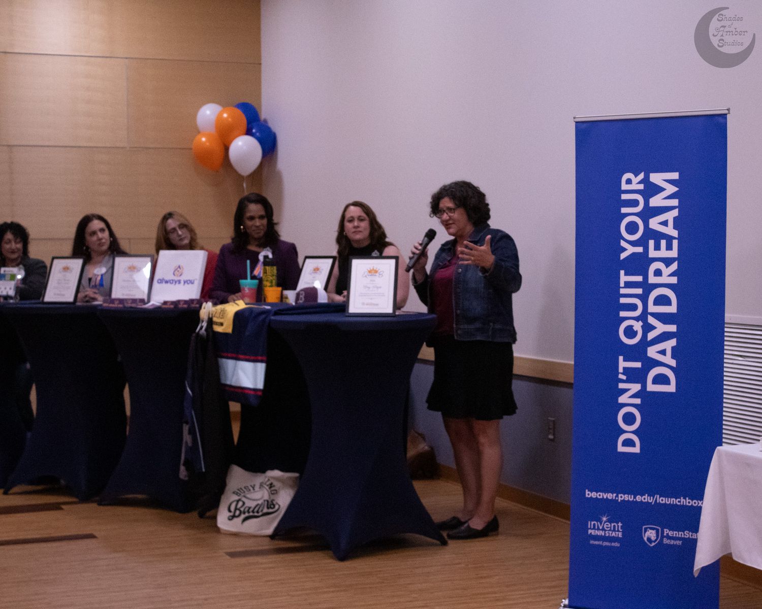 A long event banner in blue and white colors is displayed across a wall with orange and white balloons visible.