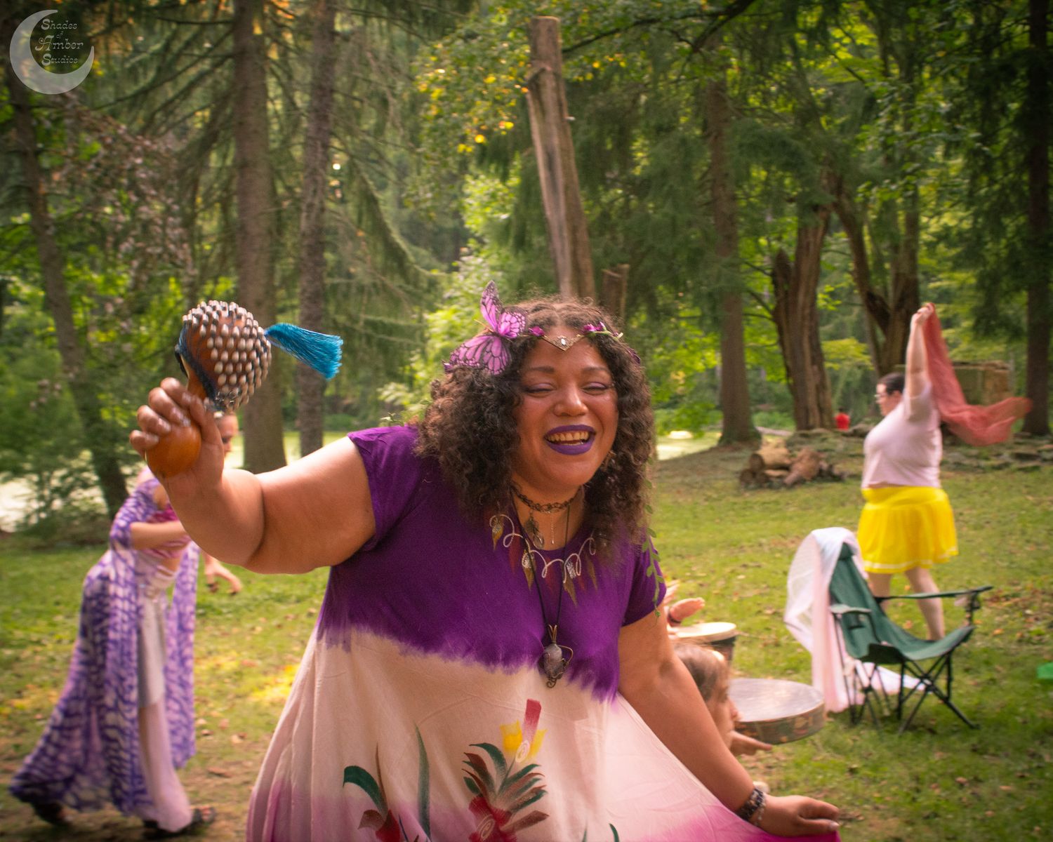 Friends in colorful dresses gather for an outdoor celebration in a lush green park setting.