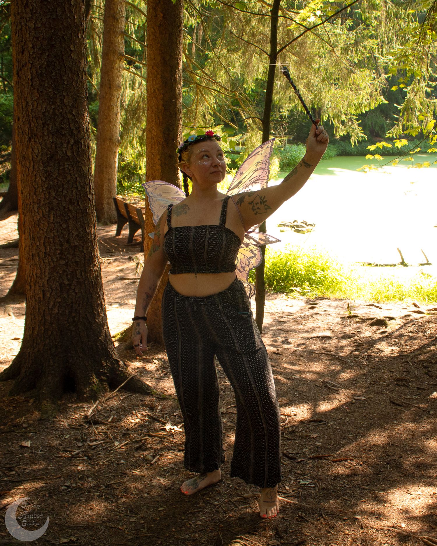 Silhouetted figure in dark clothing moves gracefully between tall pine trees in dappled sunlight.