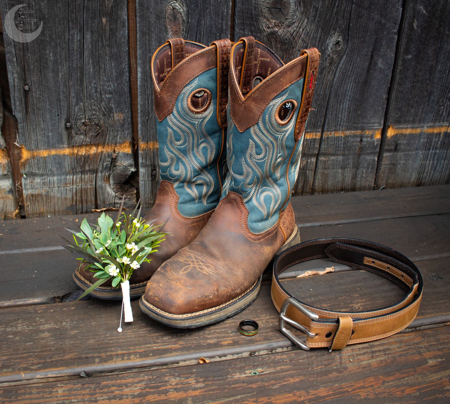Close-up view of brown leather cowboy boots with blue accents arranged in a row against a rustic wooden fence.