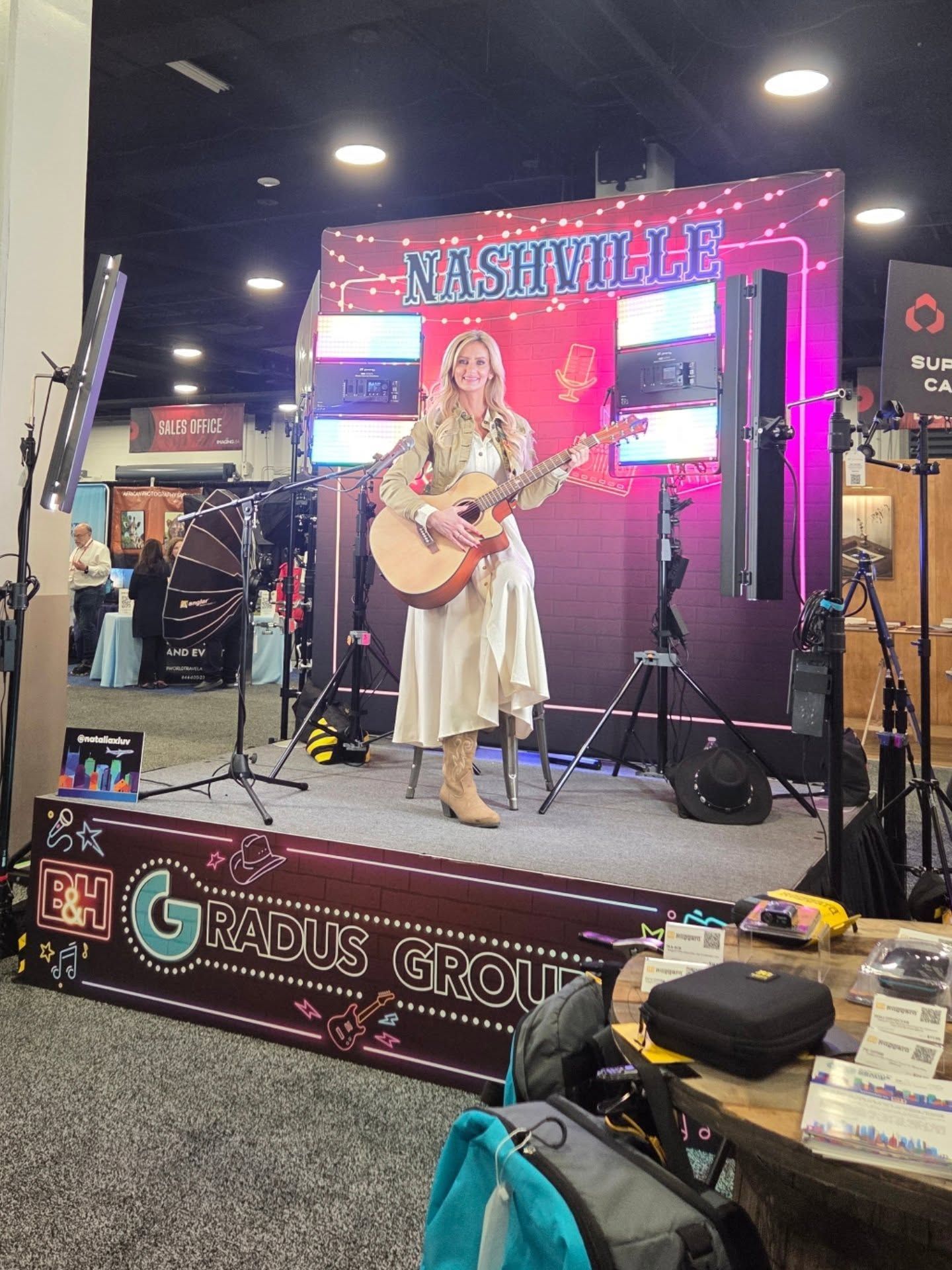 Professional studio setup with stage lights, cameras and performance area displaying colorful neon signage.