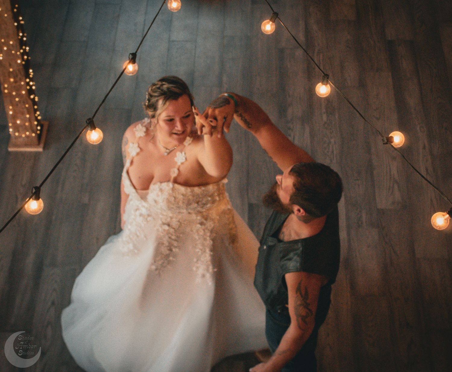A romantic dance moment under hanging string lights with a white gown swirling in motion.