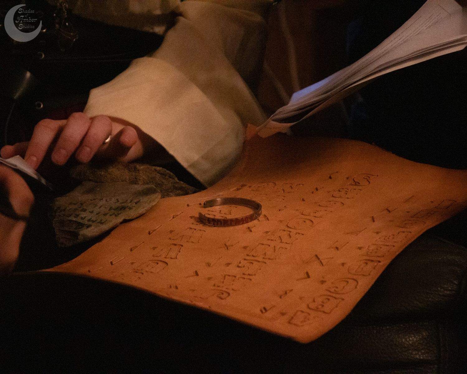 Person writing mathematical equations and formulas on white paper with black ink, viewed from above.