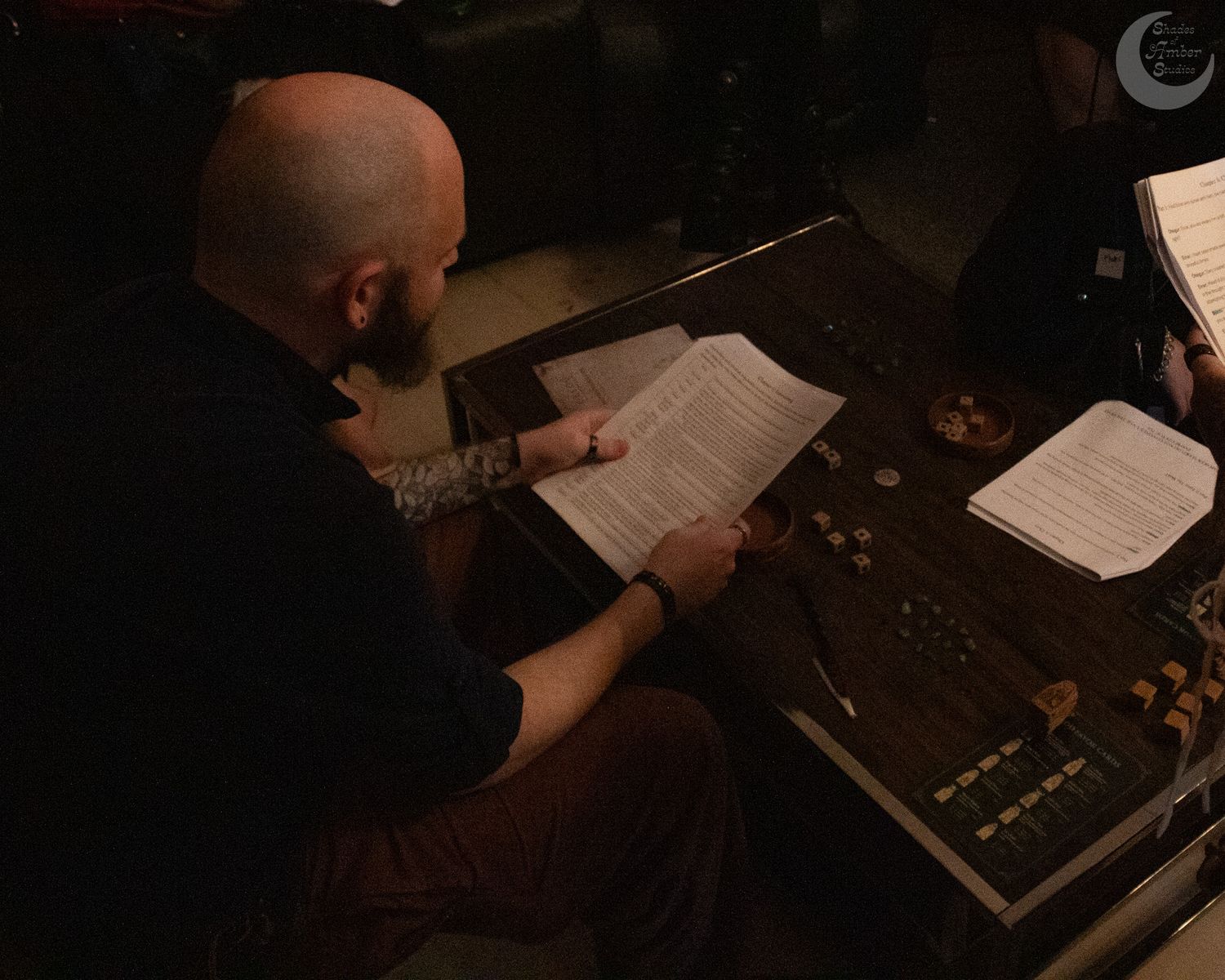 Eight dim chiaroscuro photos showing hands writing or reading in a series of dark, moody scenes.