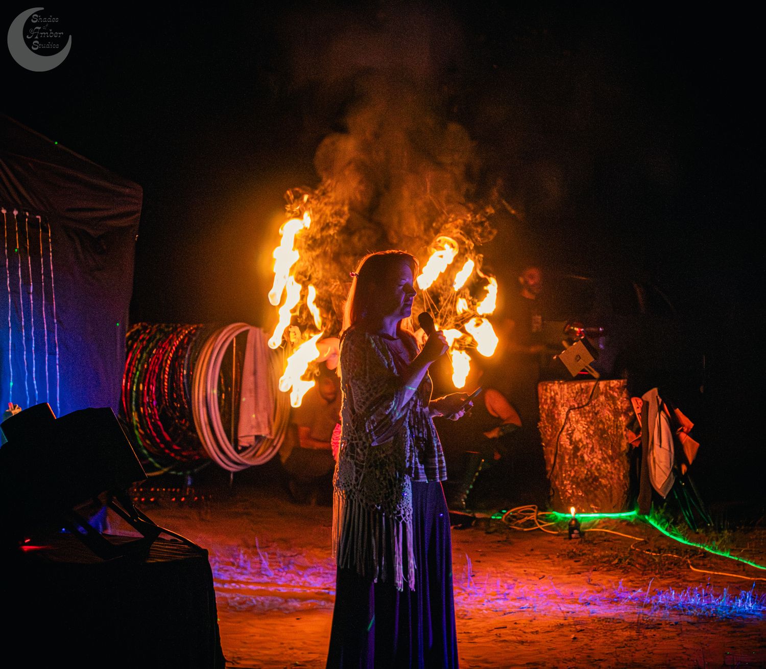 Fire performers create mesmerizing trails of light during a nighttime show with glowing torches and colorful illumination.