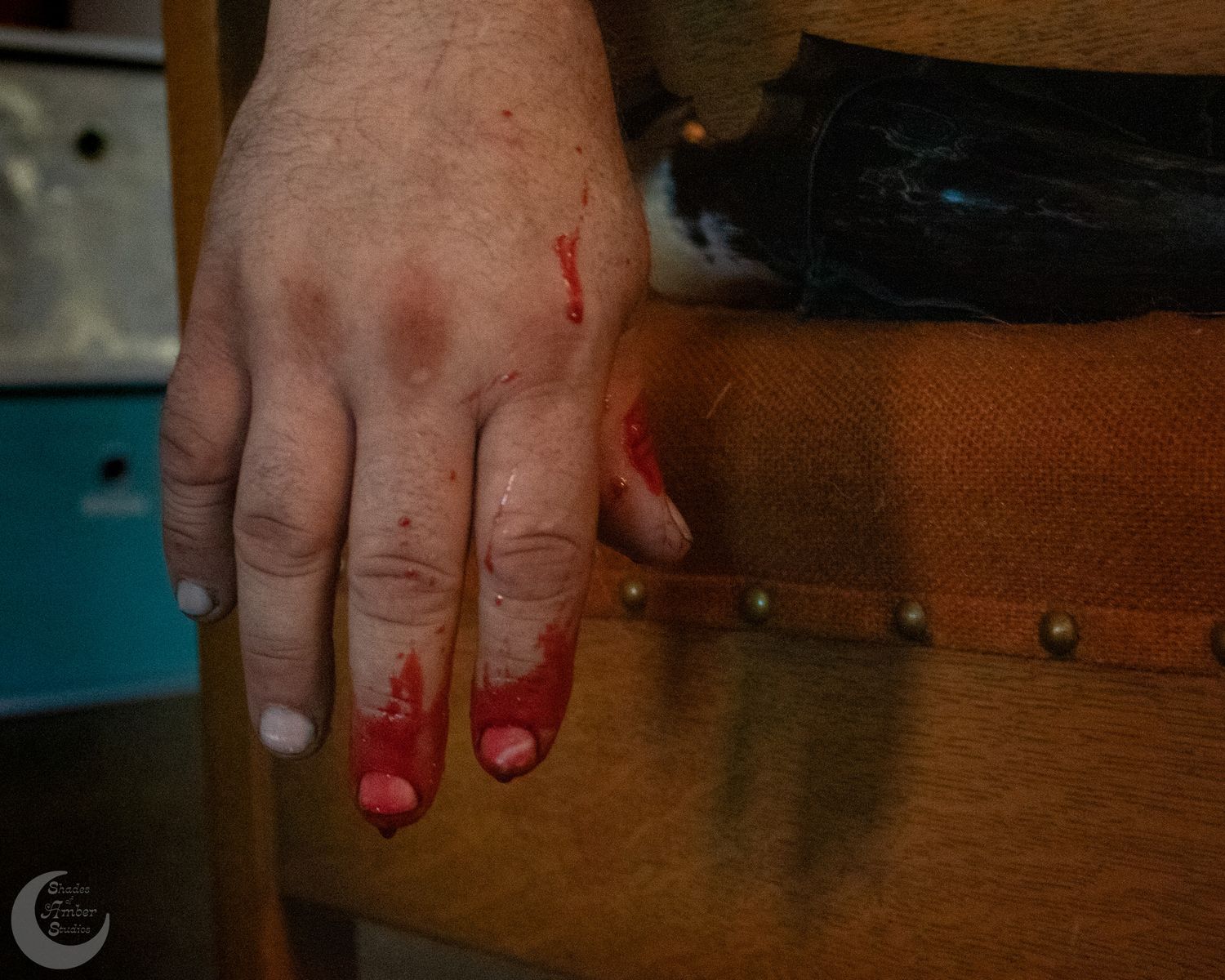Close up of hands showing painted red and white fingernails on a wooden table.