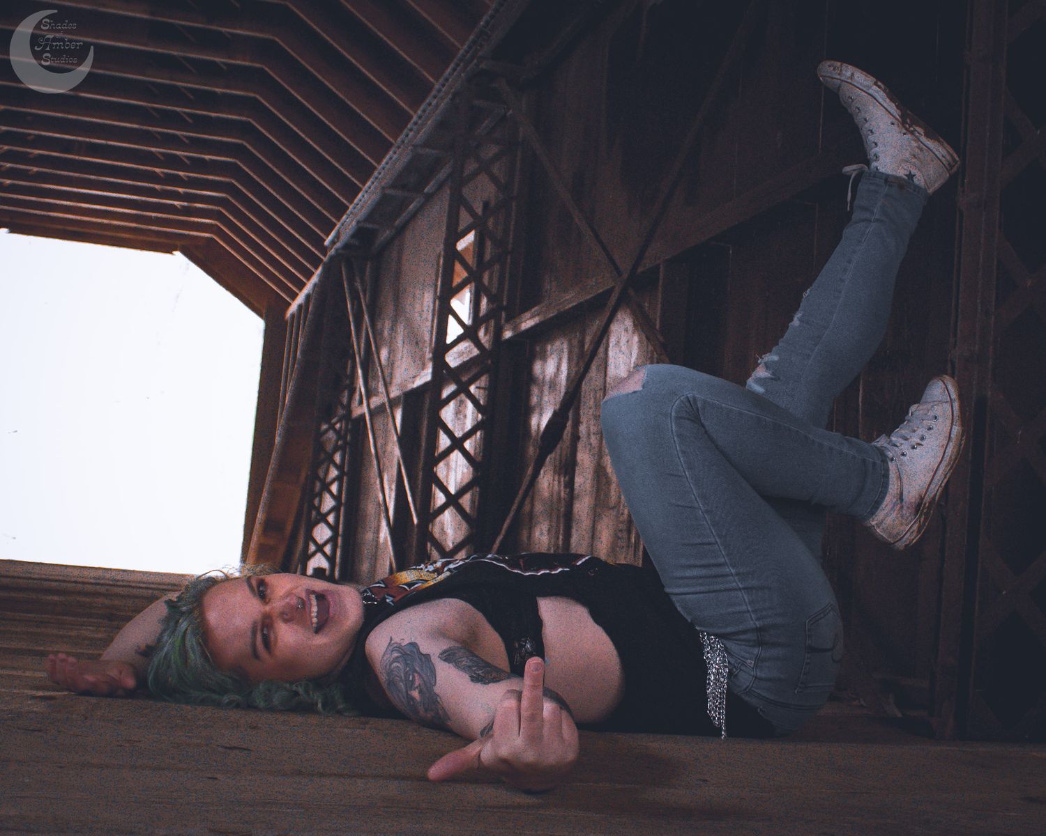 Artistic portrait showing dynamic pose on wooden bridge floor with dramatic lighting.