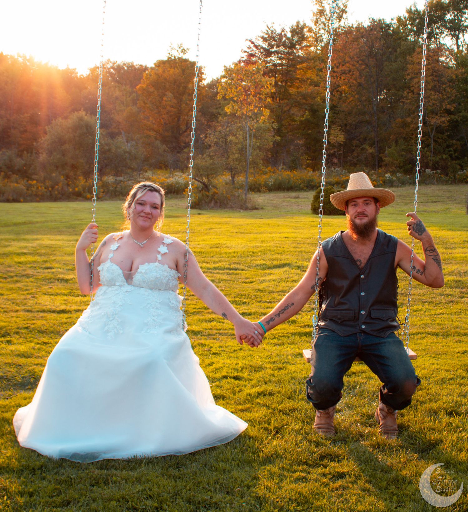 A playful wedding photo of a couple on swings during golden hour.