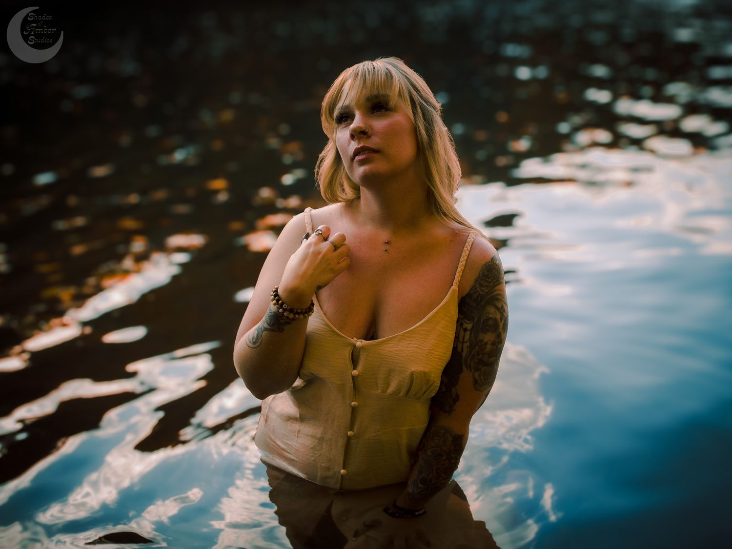A dreamy portrait by water featuring vintage-style corset and dramatic lighting.