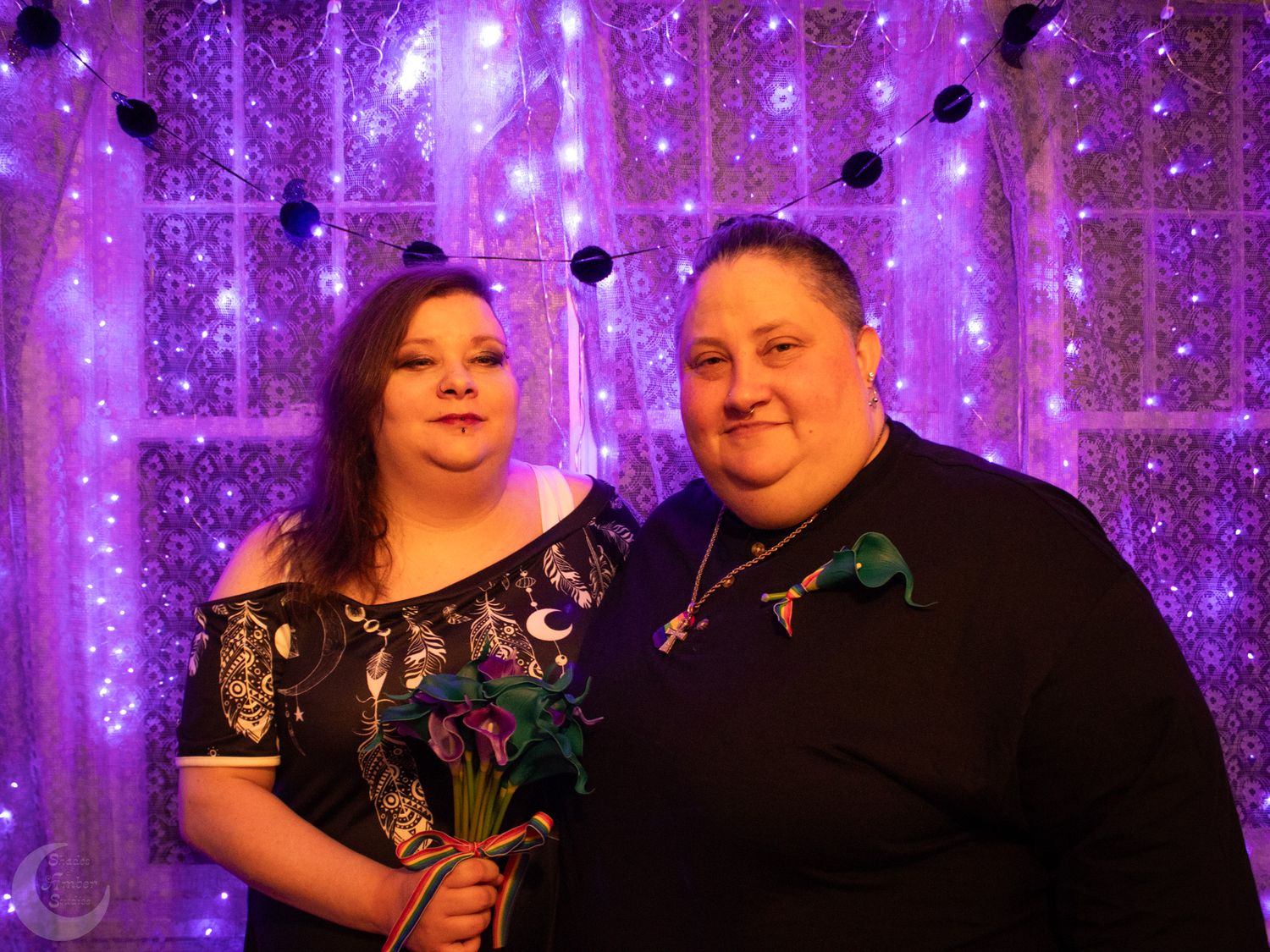 A wedding portrait featuring a couple in formal attire against a glowing purple light curtain backdrop.