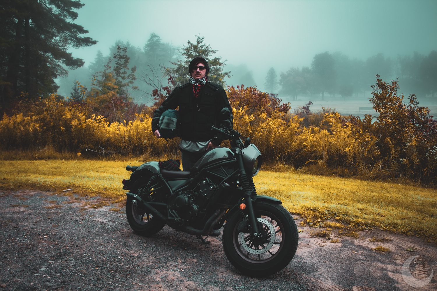 A motorcycle parked in misty golden autumn scenery during sunset.