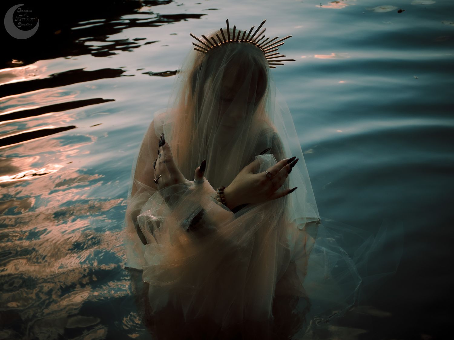 A dark and ethereal underwater scene with a figure wearing a spiked crown in turquoise water at sunset.