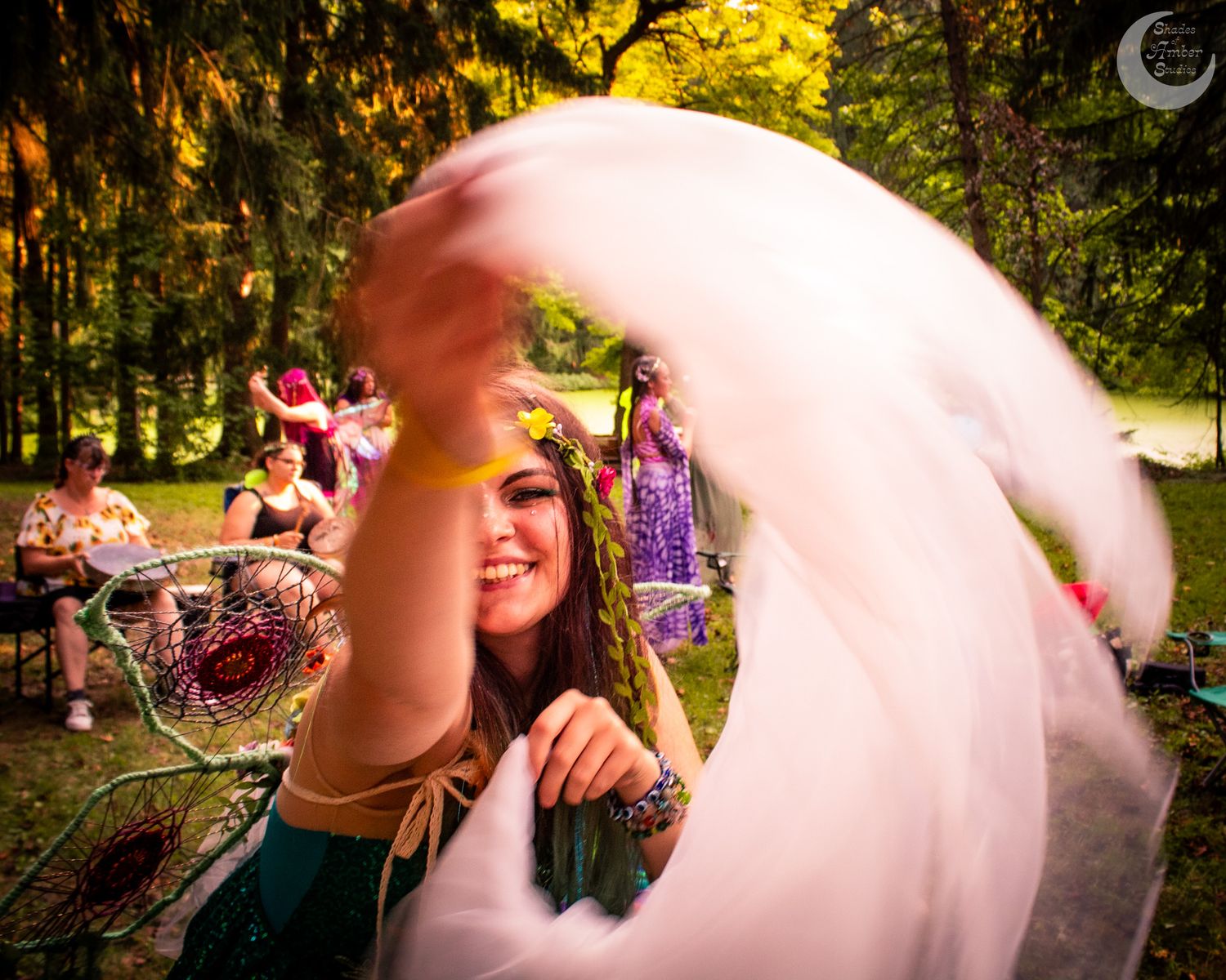 Pink fabric flows through the air during a magical forest celebration.