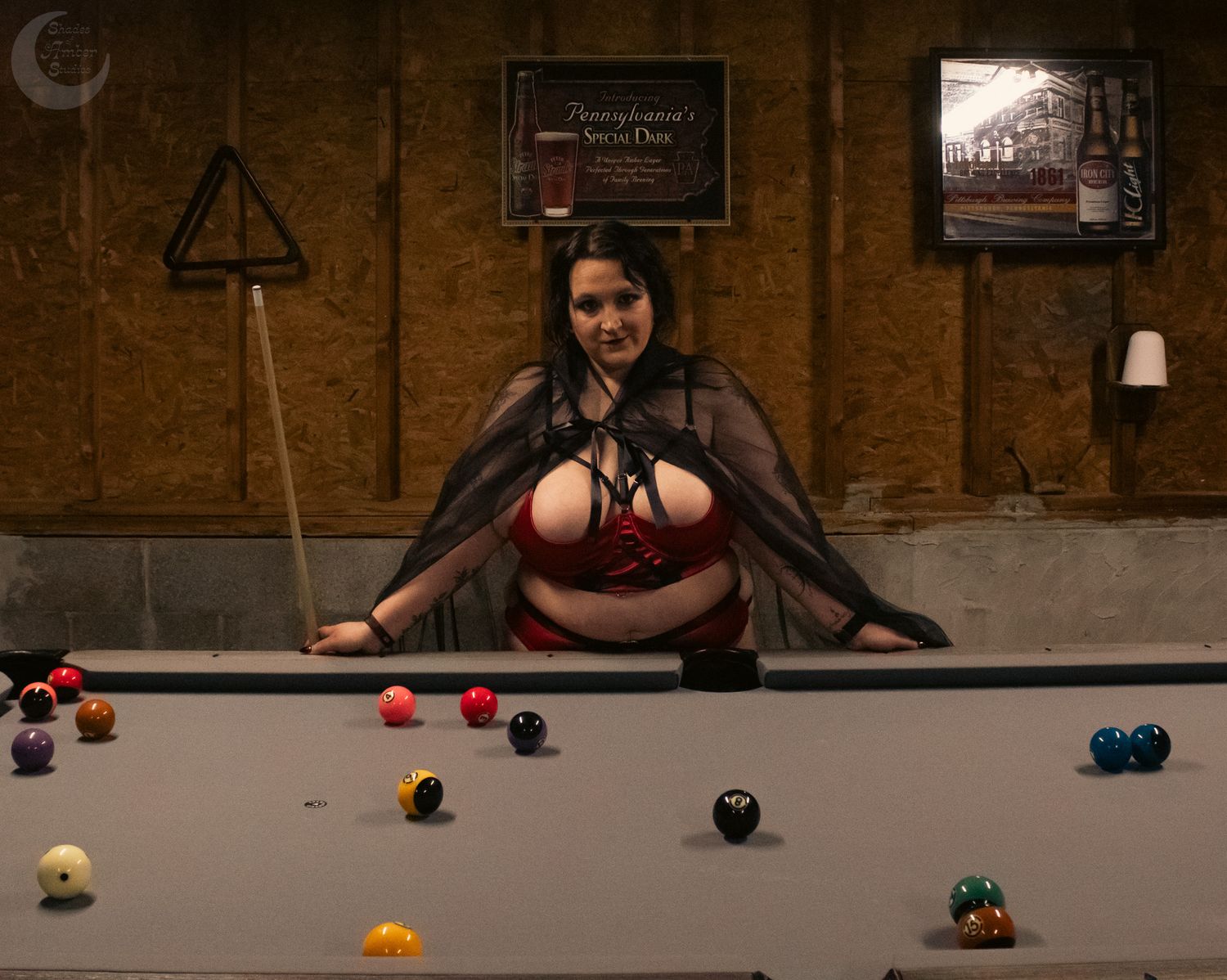 Woman in Halloween costume leaning over a pool table with billiard balls in a bar setting.