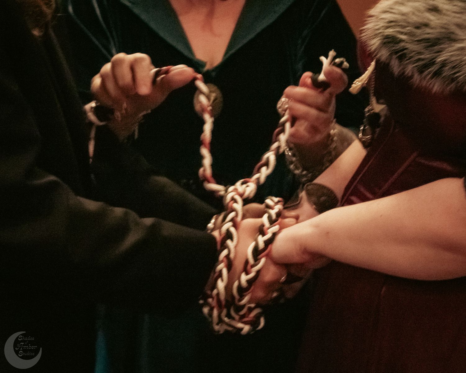 Close-up shot of hands performing a traditional handfasting ritual with braided cords.