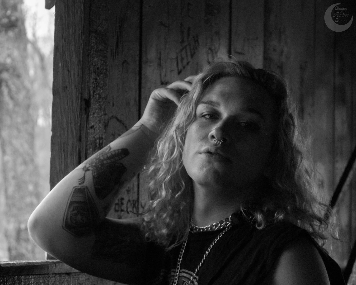 Dramatic black and white portrait showing contemplative pose against wooden background.