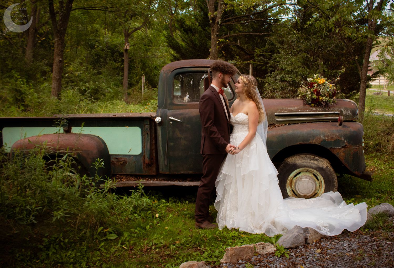A rustic wedding photo shoot featuring vintage pickup trucks and white gowns in a scenic outdoor setting.