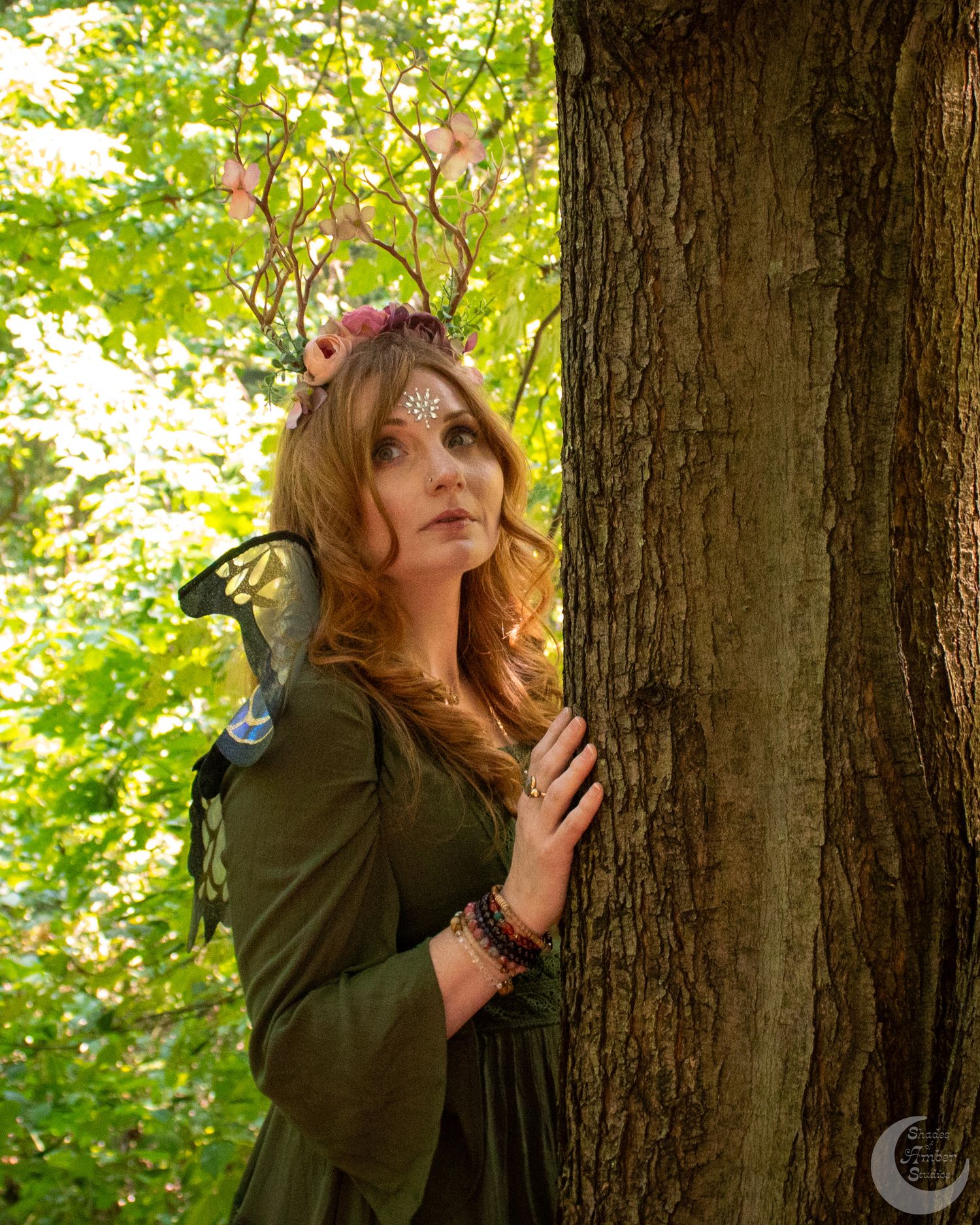A mystical forest photoshoot with dramatic poses against a sunlit backdrop of green leaves.