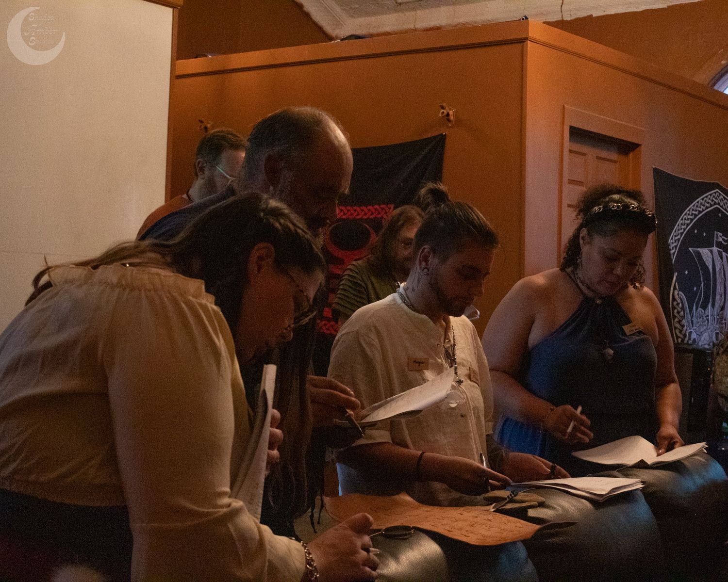 People huddled together studying or learning in a room with warm lighting and a casual atmosphere.