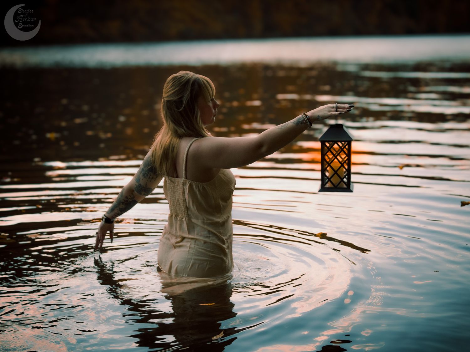 Moody water scene with vintage lantern creating mystical reflections at sunset.