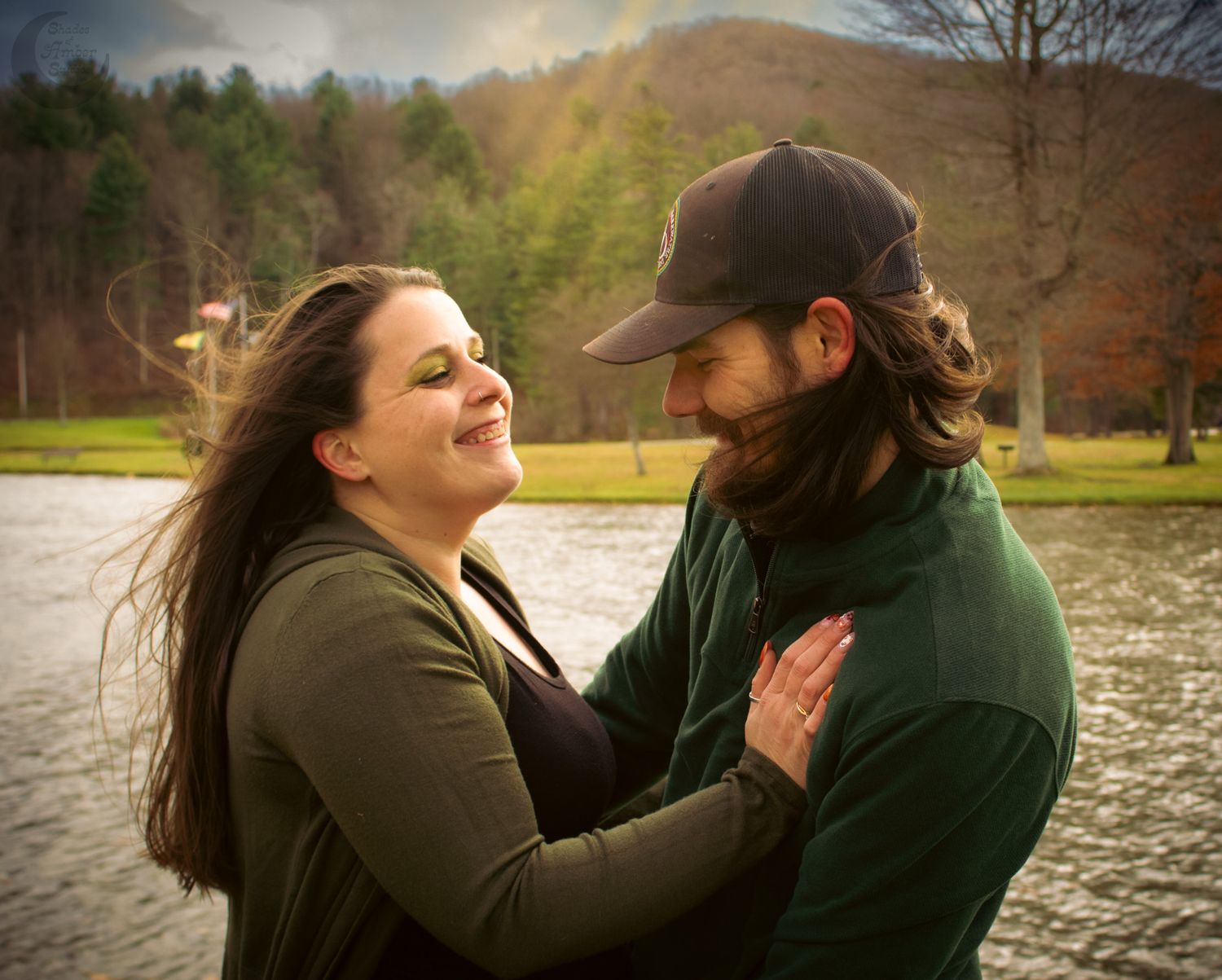 A couple shares a joyful moment together outdoors on an autumn day with mountains and trees in the background.