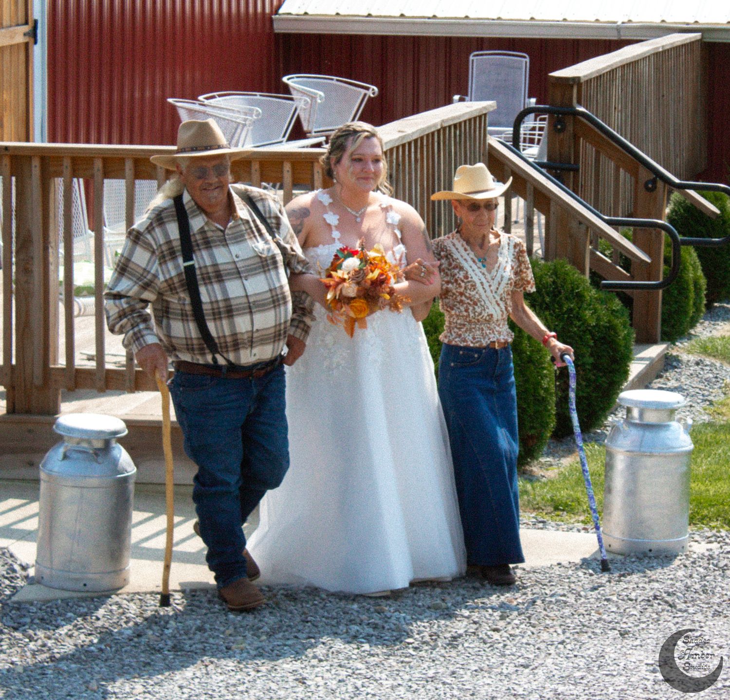 Wedding party gathered outside a red barn with vintage milk cans.