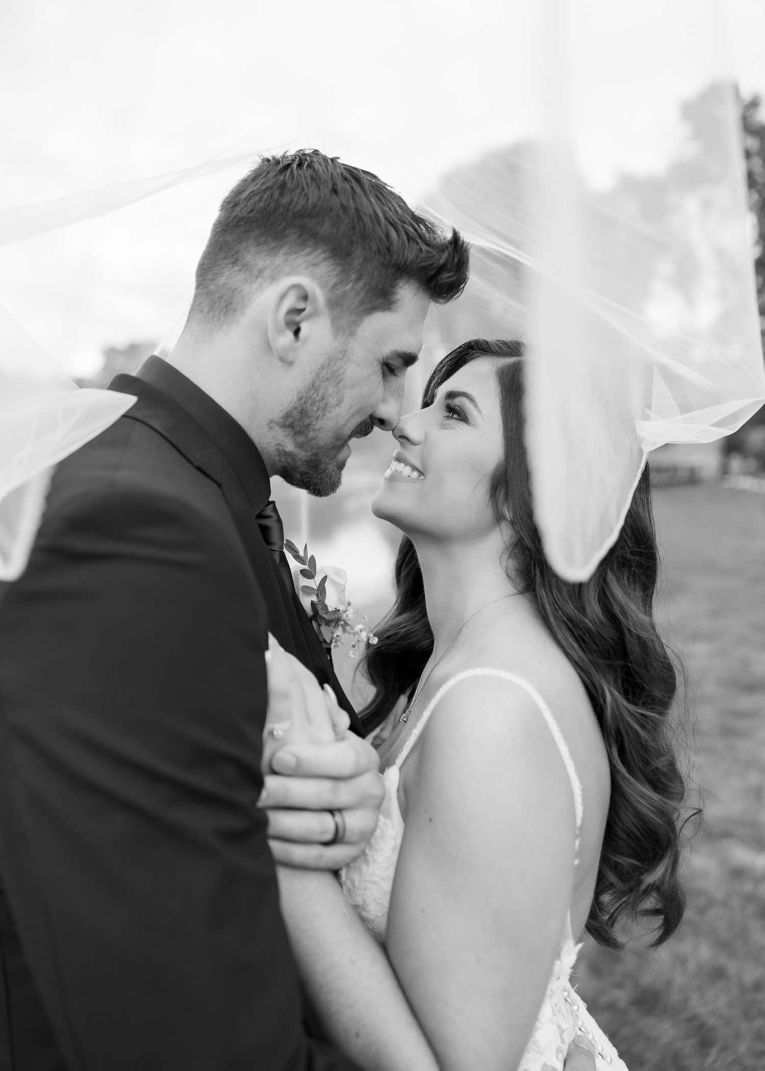 A romantic black and white wedding photo of a couple sharing an intimate moment under a veil.