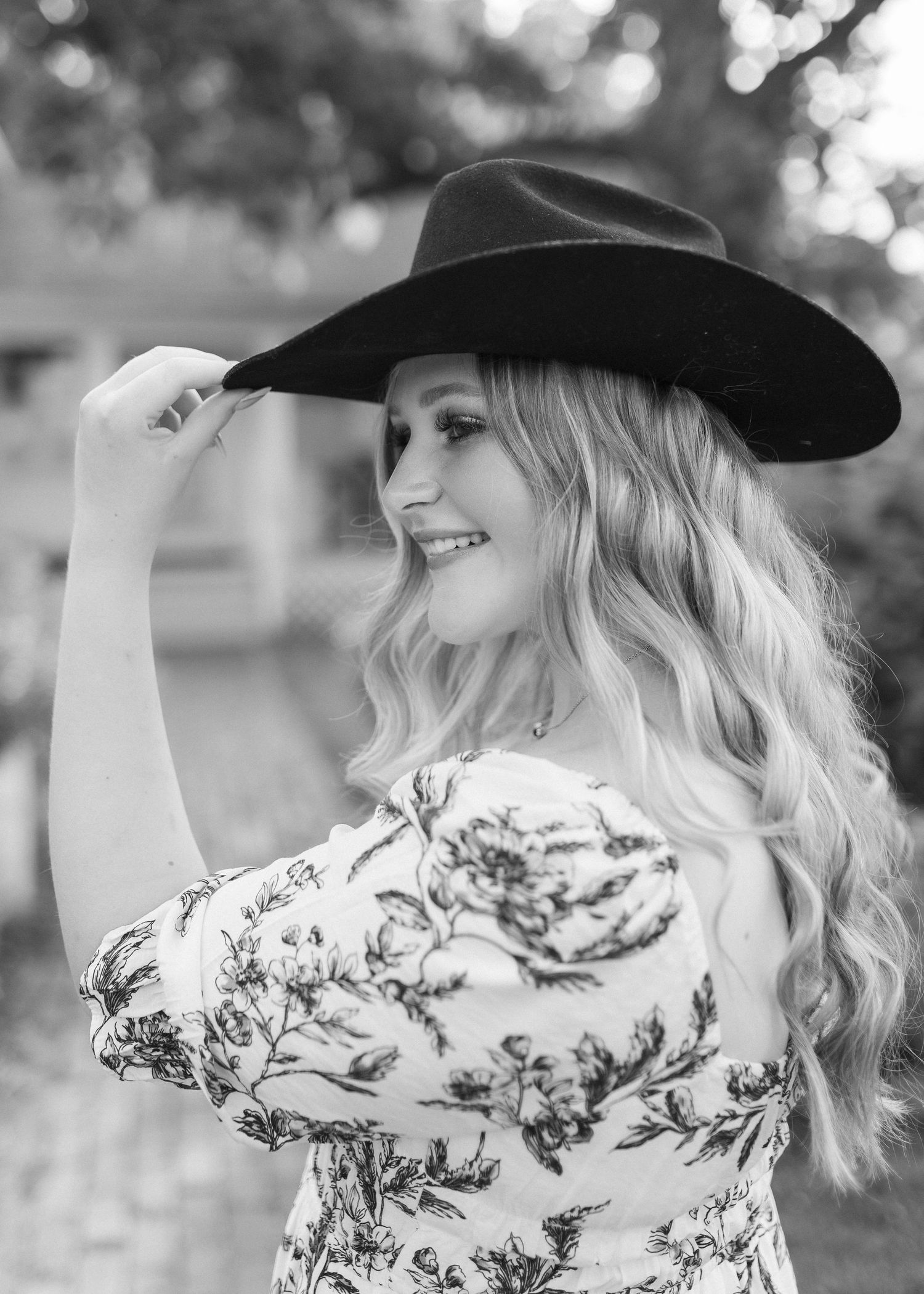 Black and white portrait series featuring a floral dress and black cowboy hat against natural backdrop.