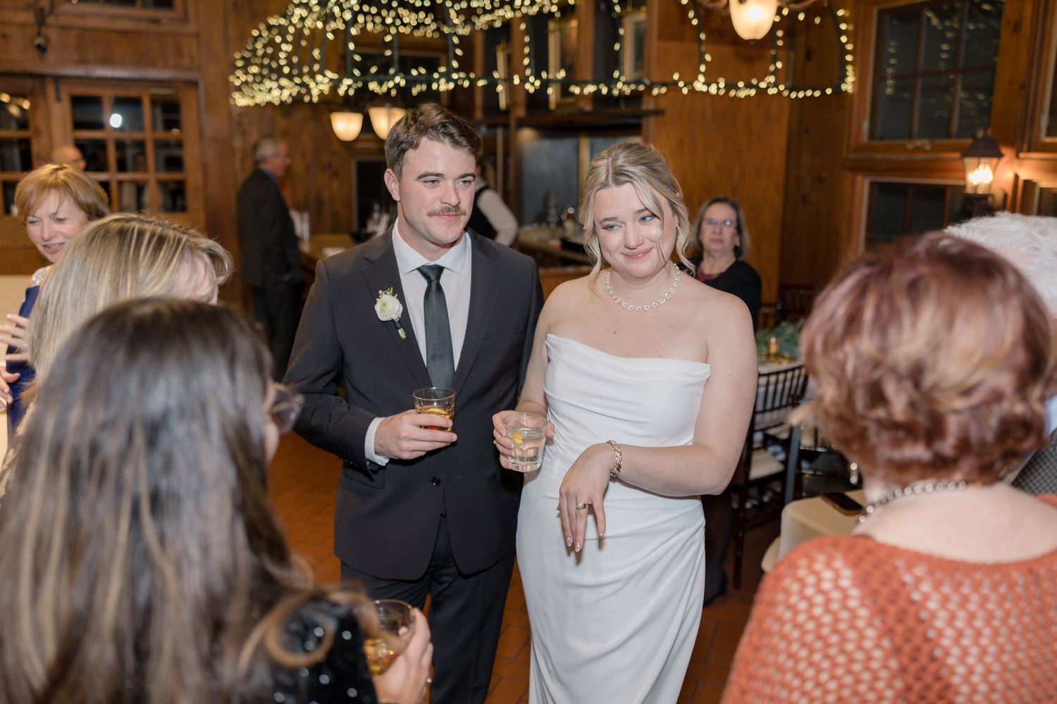 Wedding celebration in rustic venue decorated with string lights.