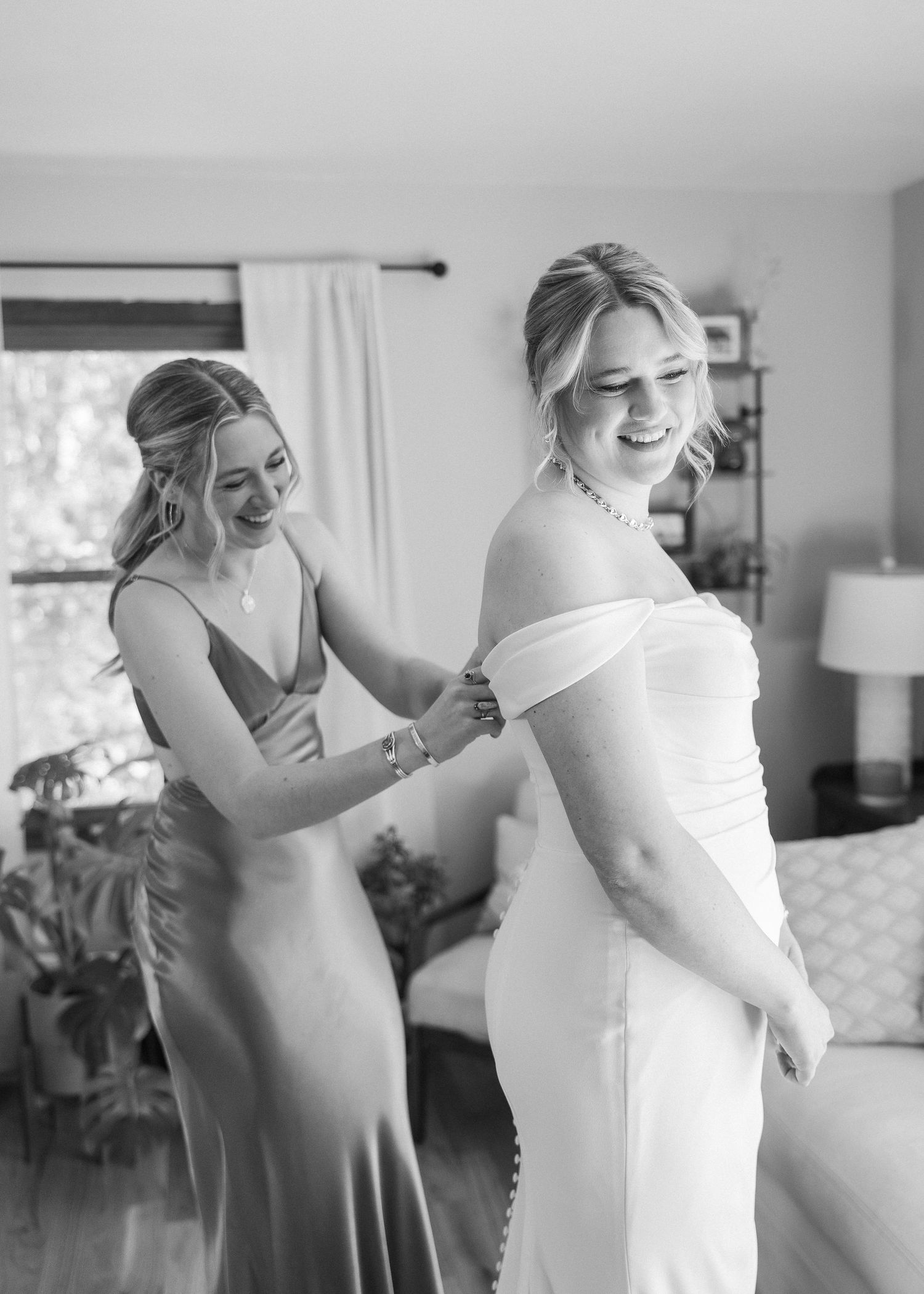 A joyful moment during wedding dress preparations in a sunlit room.