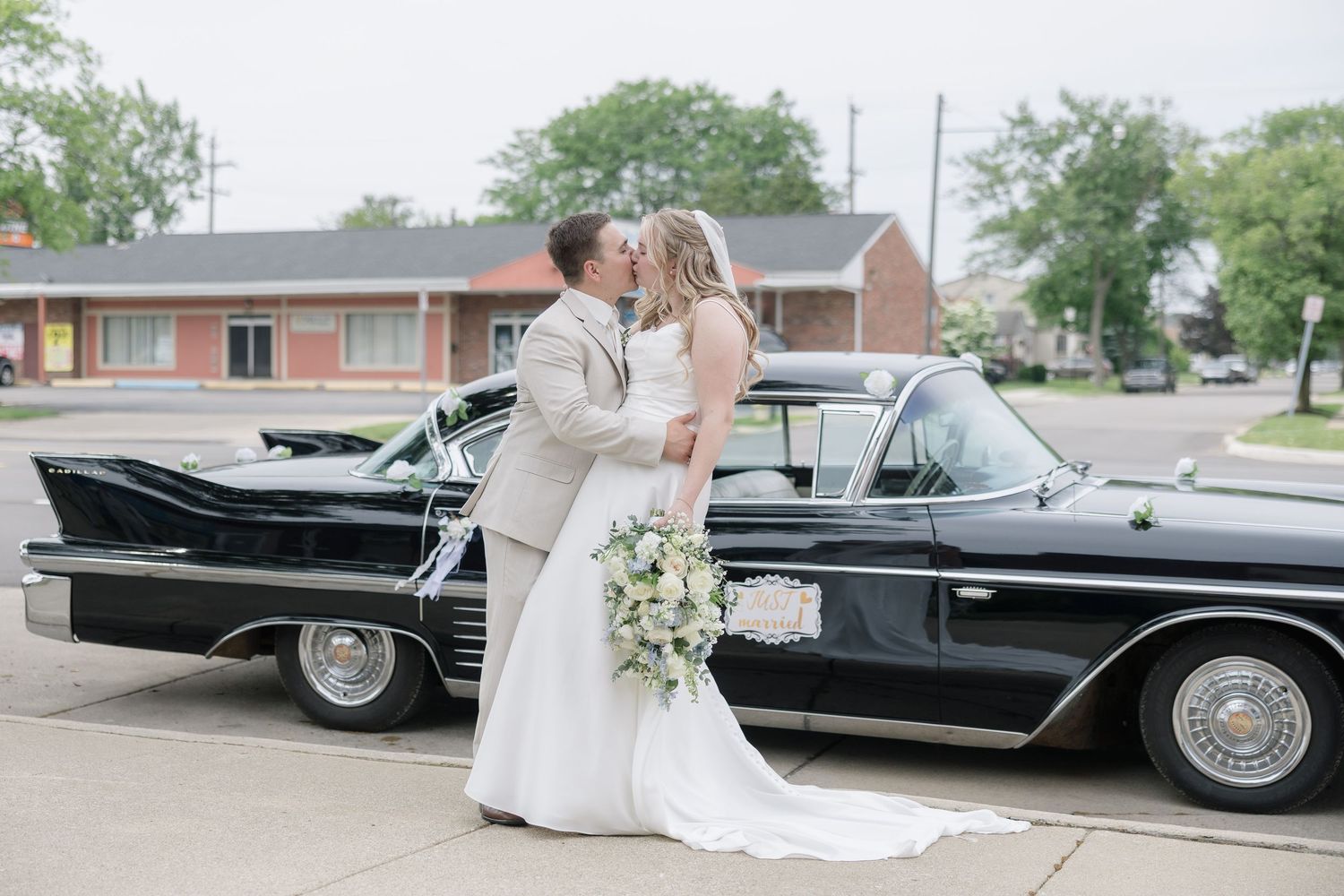 Wedding couple posing with a classic black vintage car on their special day.