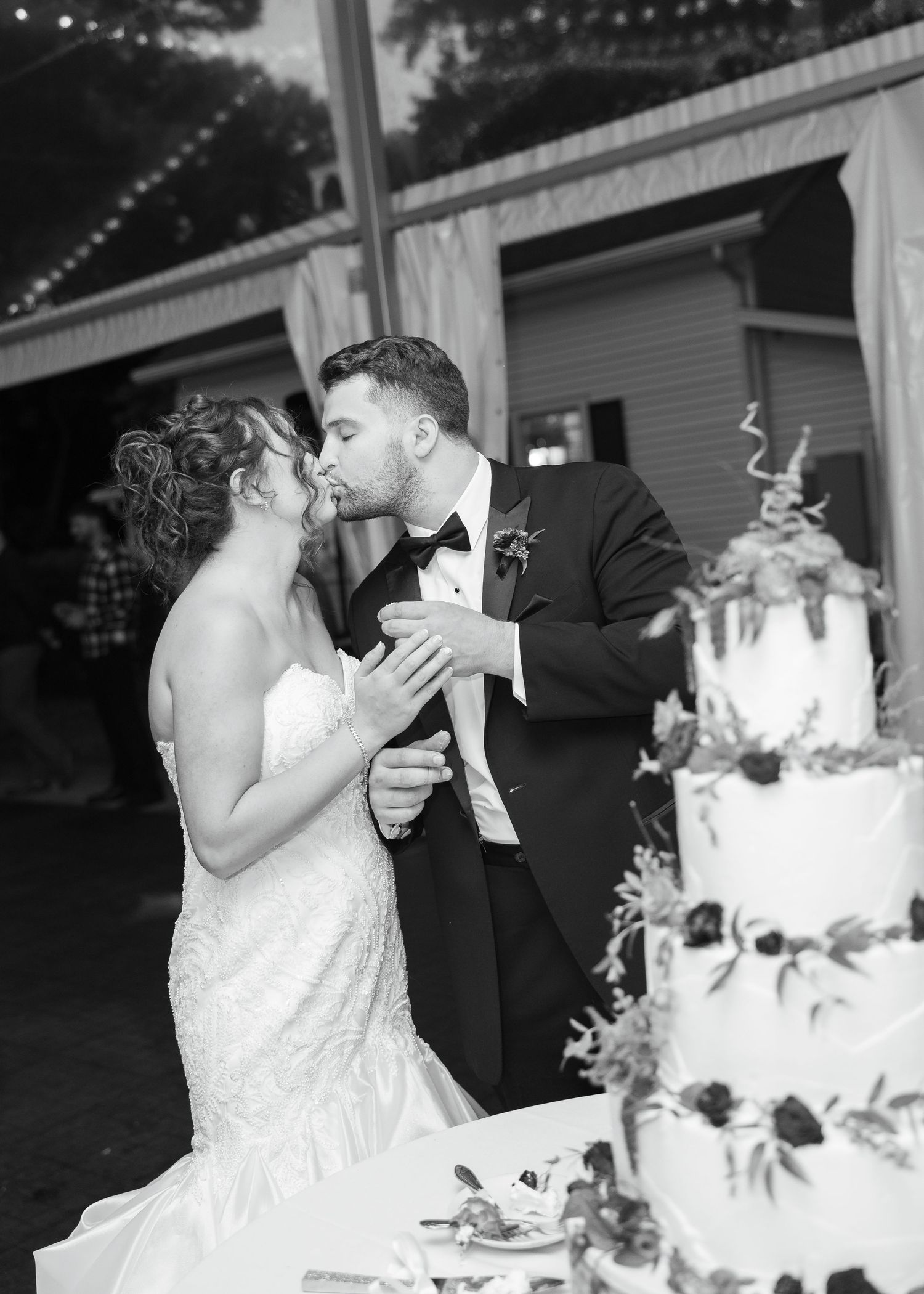 Black and white wedding photos showing a couple cutting their elegant white cake at their reception celebration.