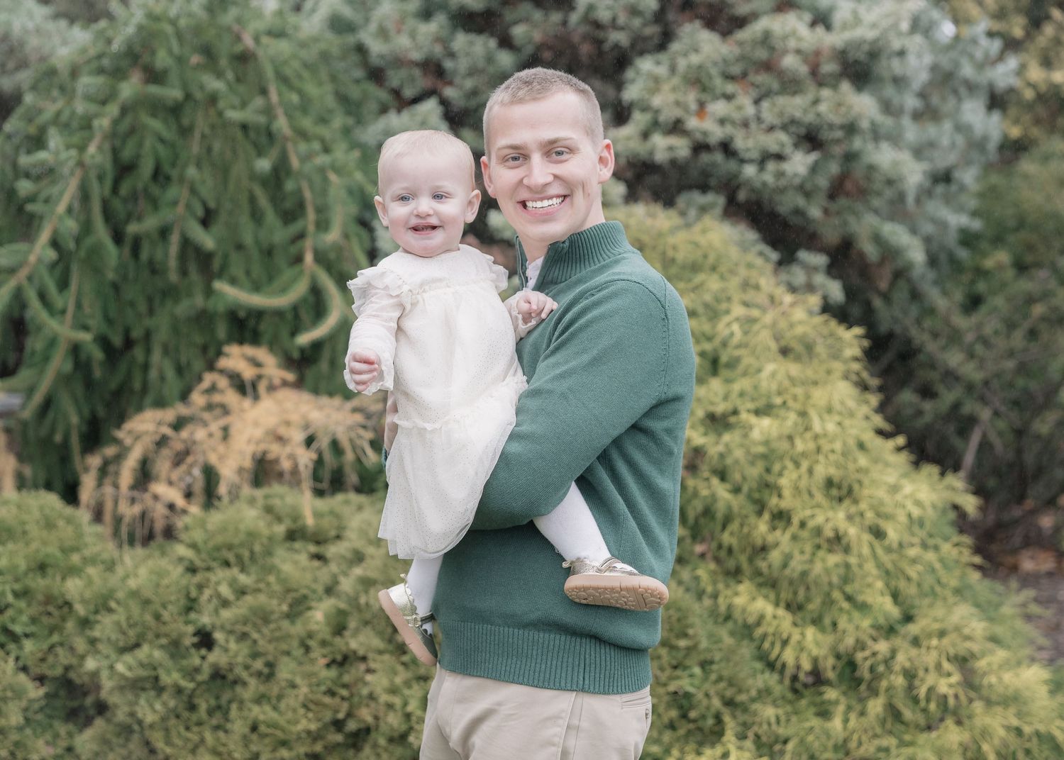 A parent and child share tender moments together in a lush garden setting during a family photo session.