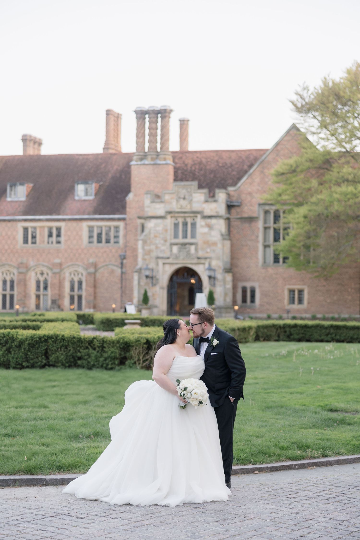 Wedding portraits in front of a grand historic brick mansion with manicured grounds.