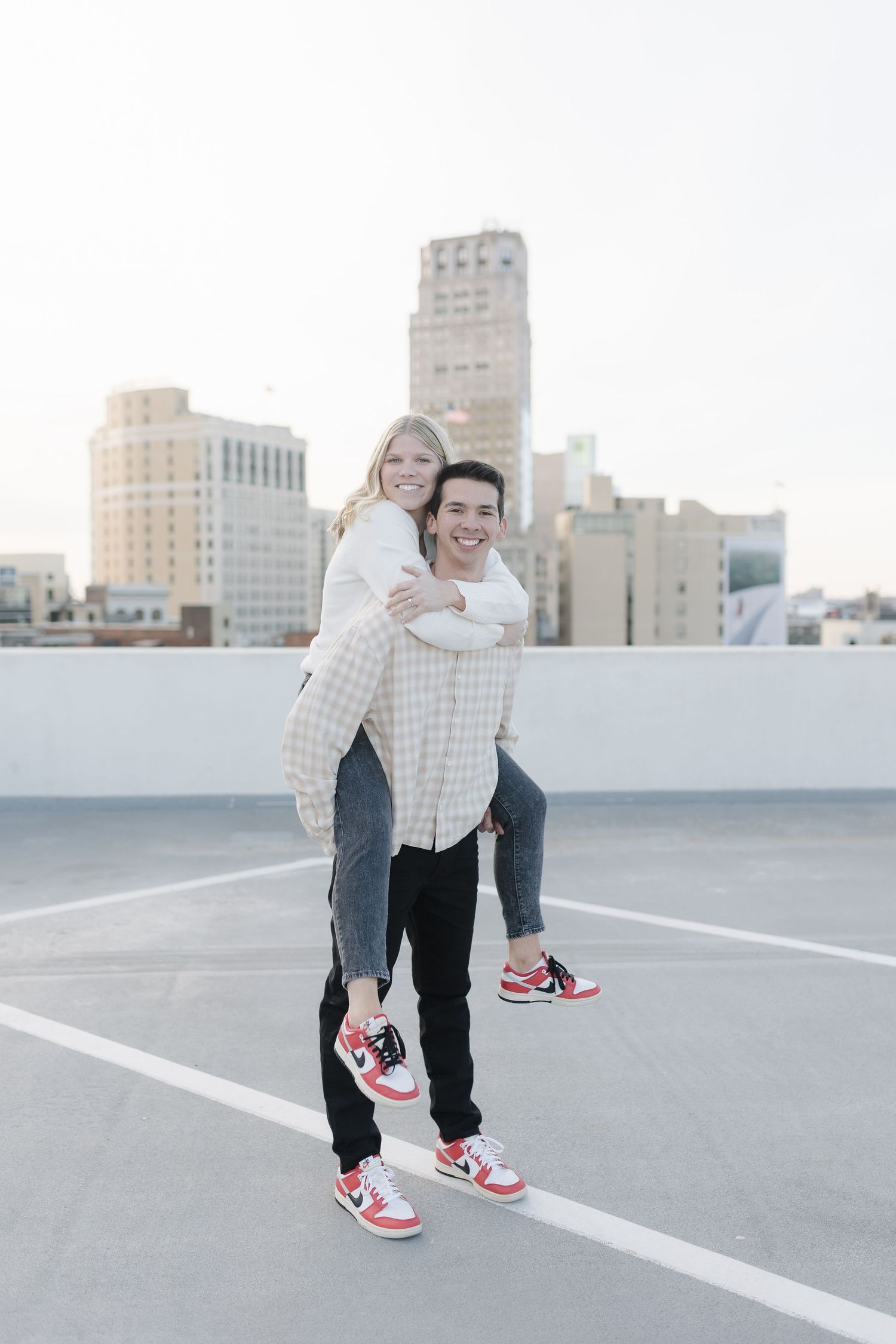 Playful couple in matching sneakers having fun with a piggyback ride on an urban rooftop.