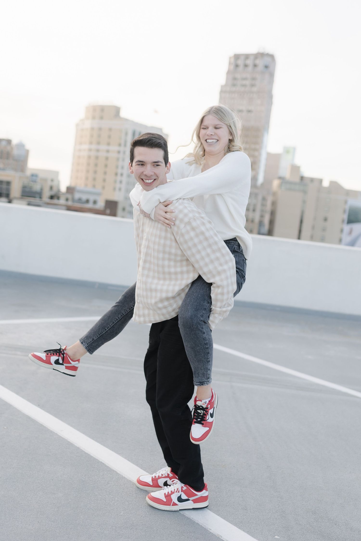 Playful piggyback ride on an urban rooftop with matching sneakers and city views.