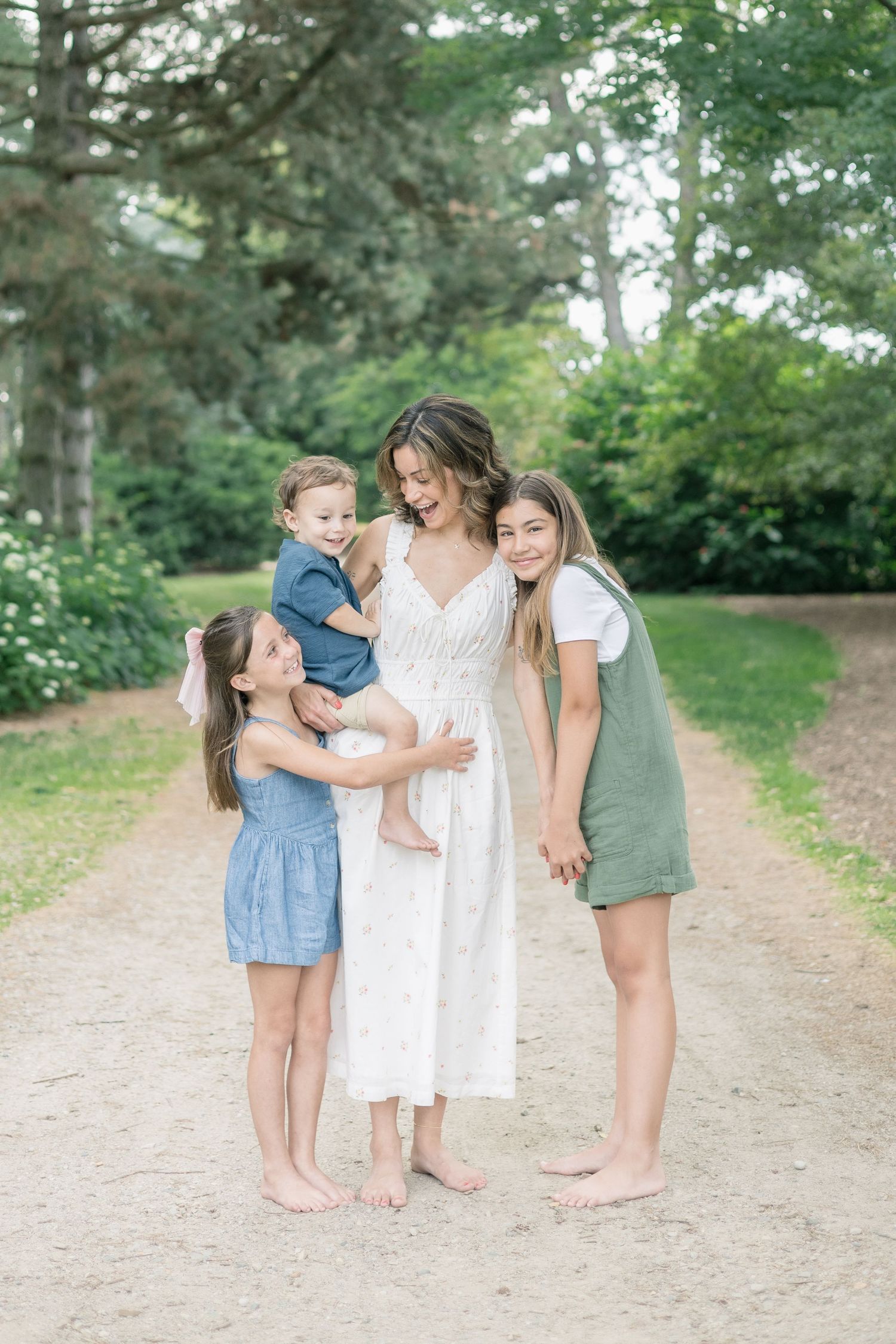 Family members share tender moments together on a sunlit outdoor trail.