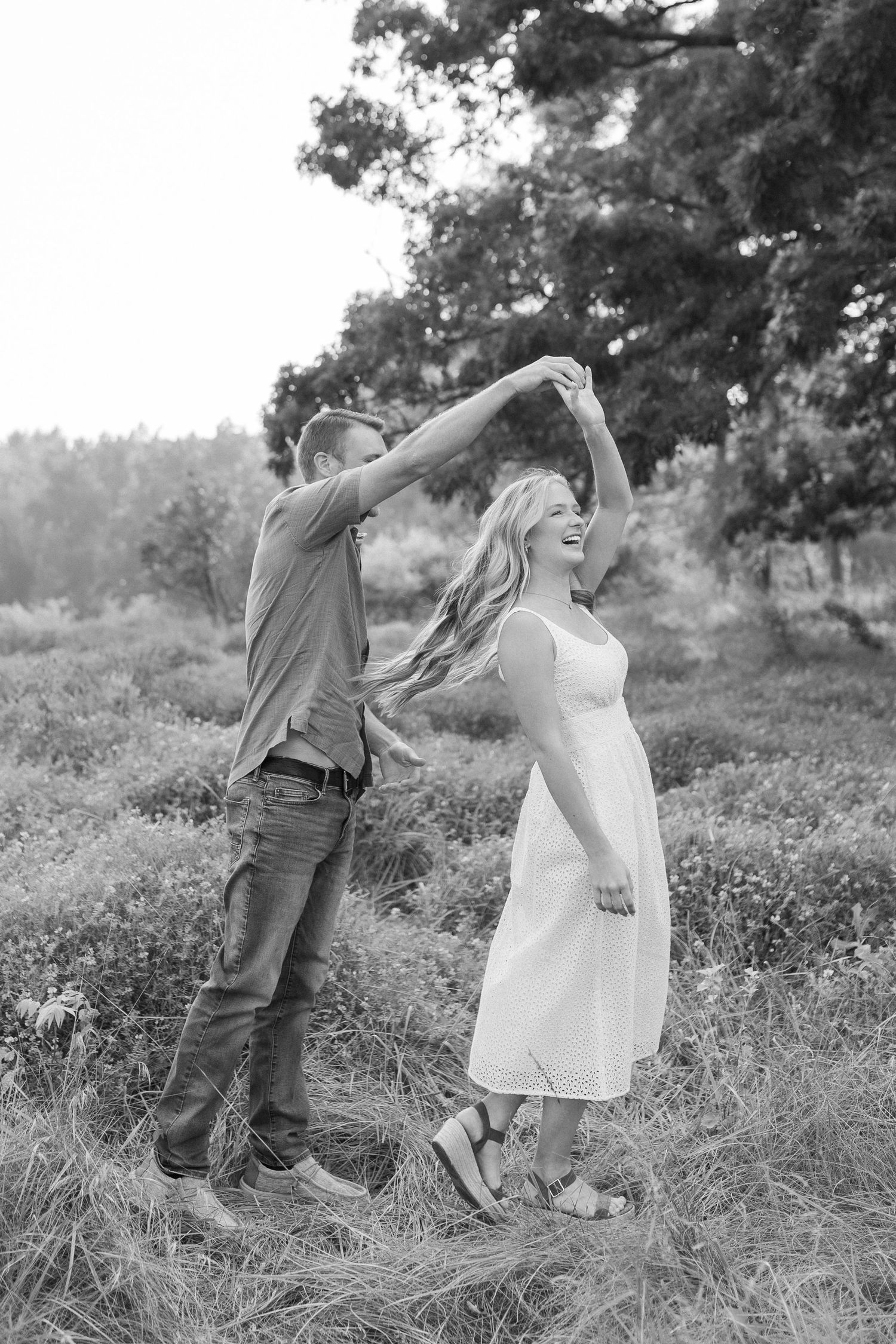 A couple dances playfully together in a meadow filled with wildflowers on a sunny summer afternoon.