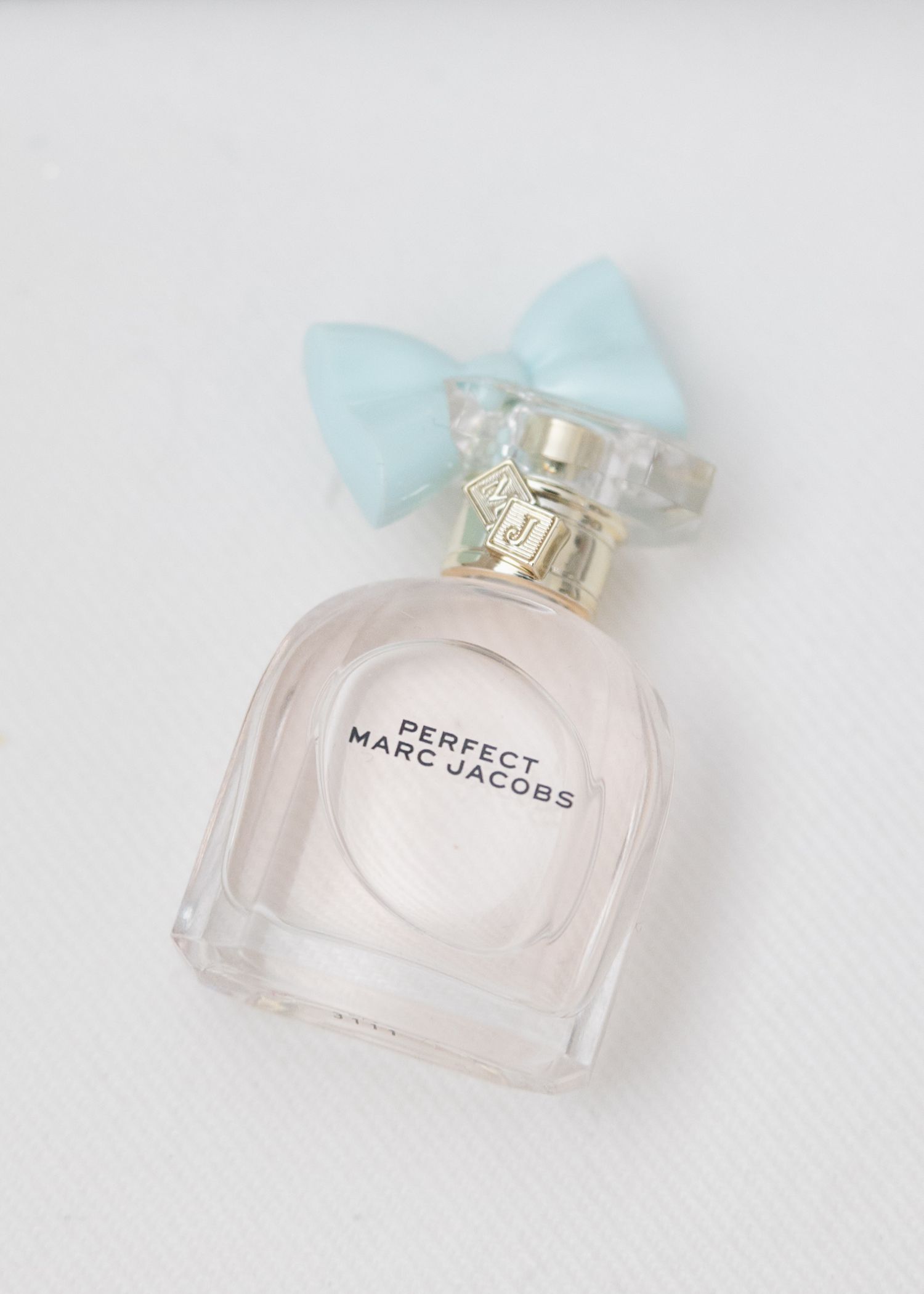 Perfect Marc Jacobs perfume bottle with light blue bow on white background.