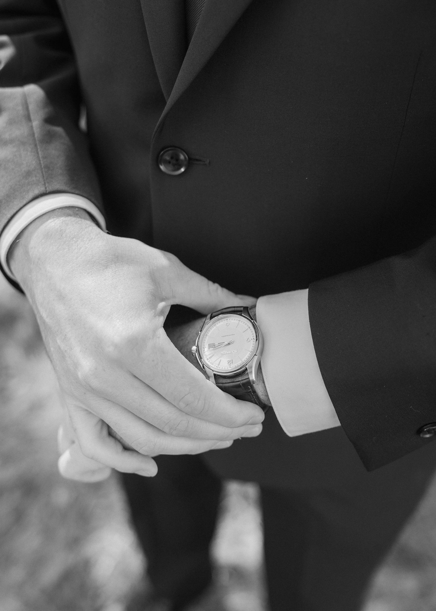 Close up of a dress watch on formal suit sleeve with black and white detail.