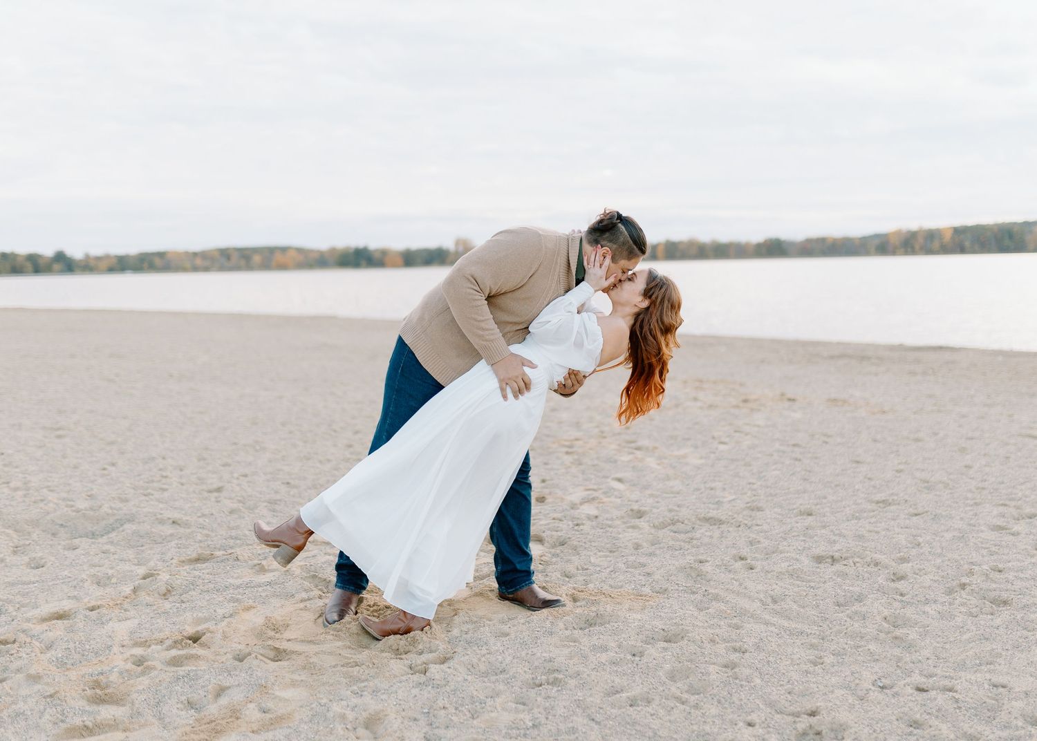 Couple dancing together on a sandy beach at sunset.