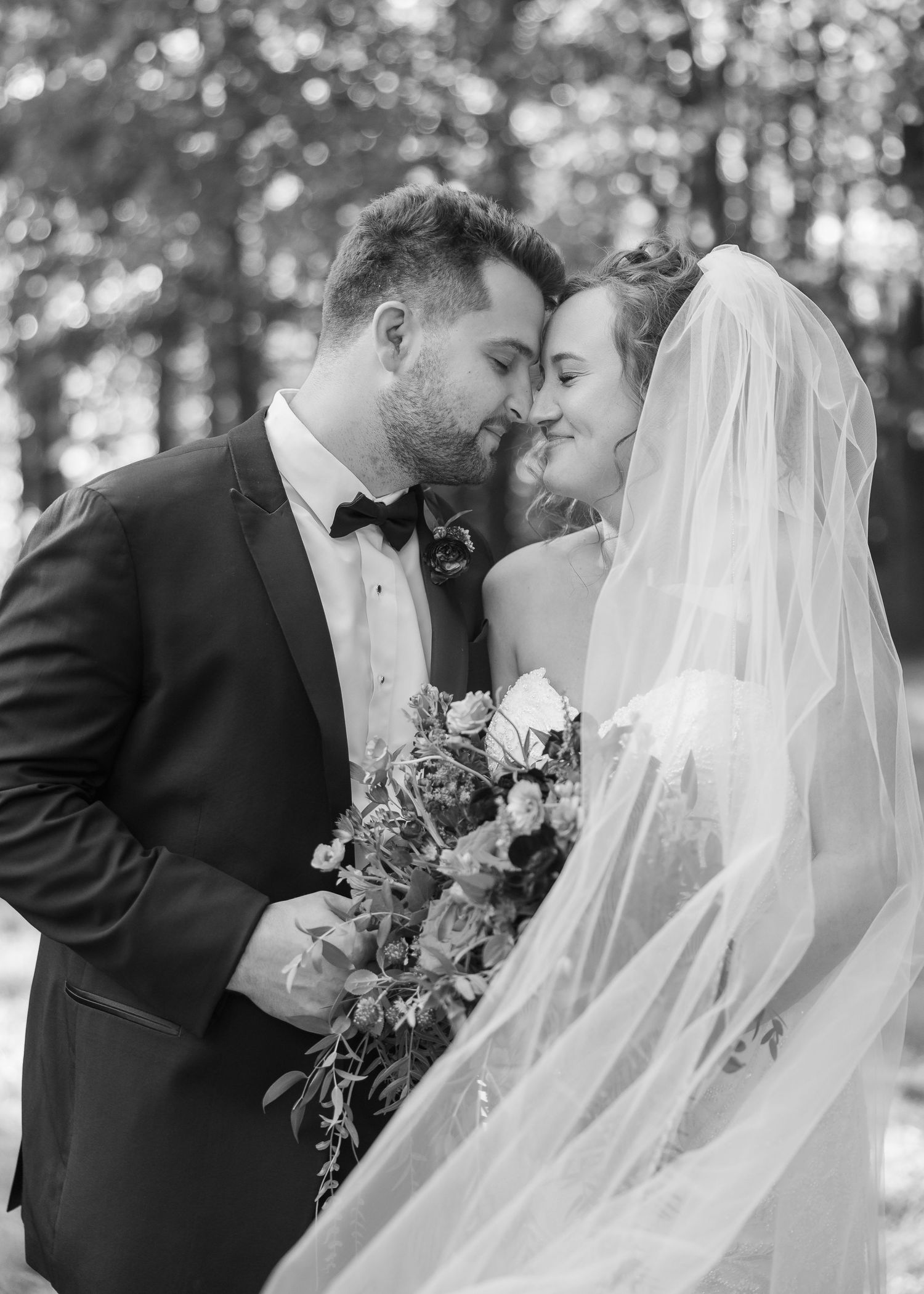 A romantic black and white photo series of newlyweds sharing intimate moments under a flowing white veil.