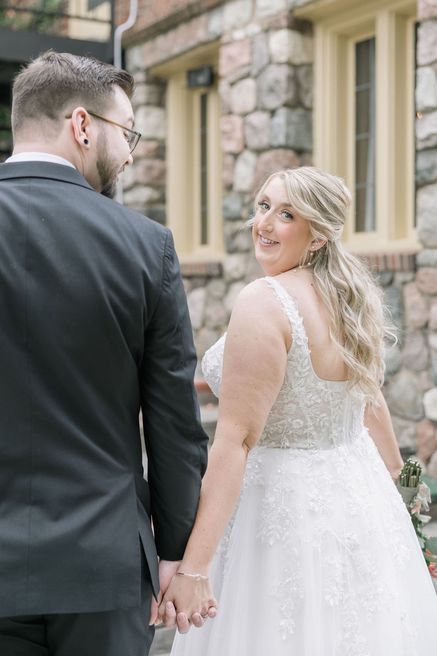 A romantic sequence of wedding photos showing a couple in formal attire walking together against a stone wall backdrop.