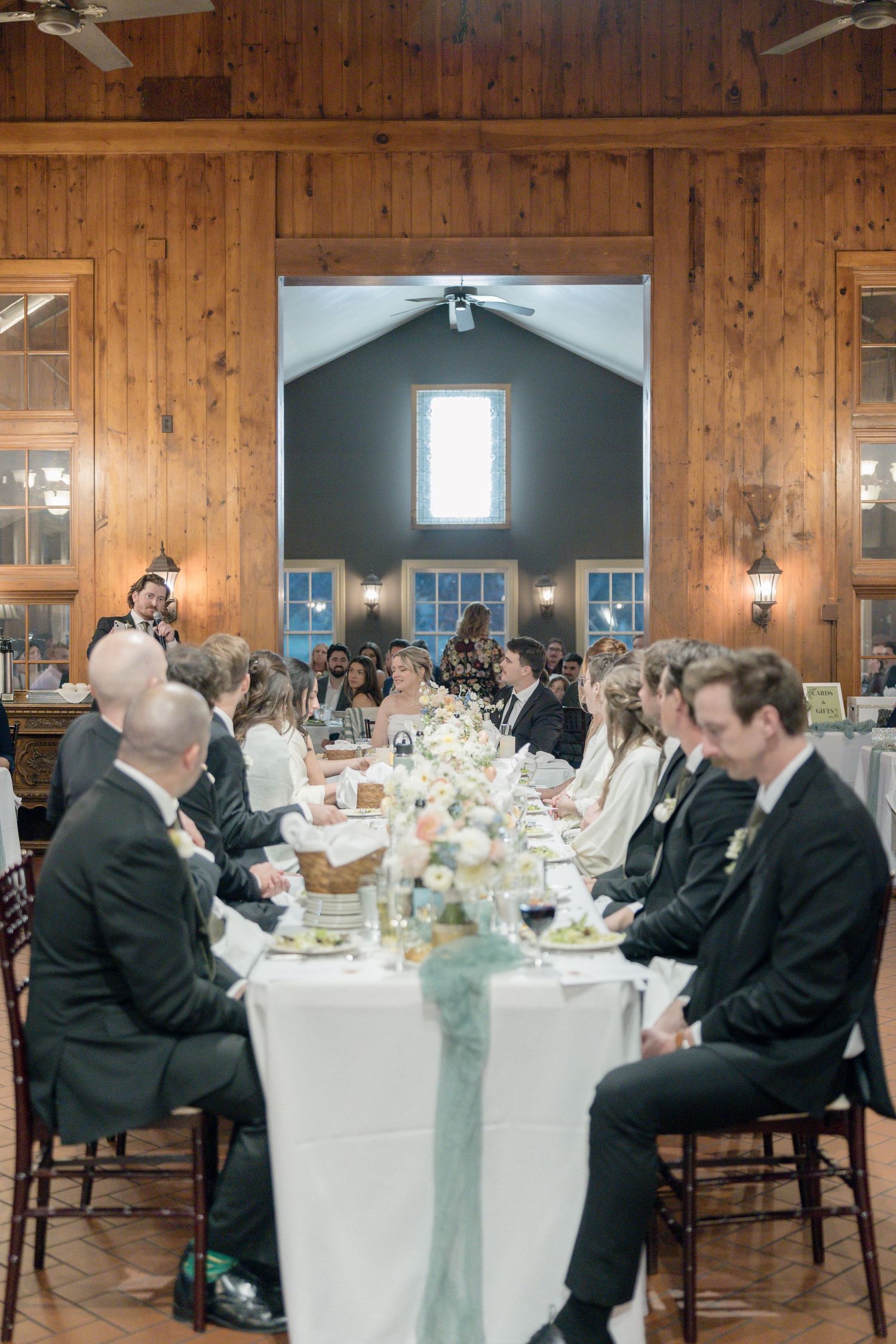 Wedding reception in rustic wooden venue with long tables and formal place settings.
