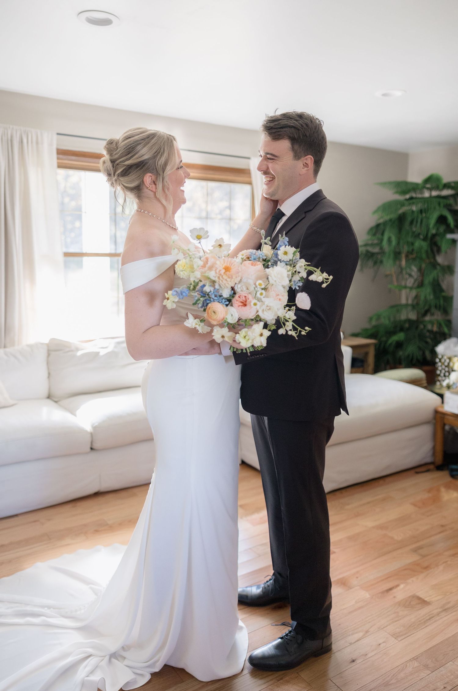 A joyful wedding moment showing the couple sharing a laugh while holding a pastel floral bouquet.