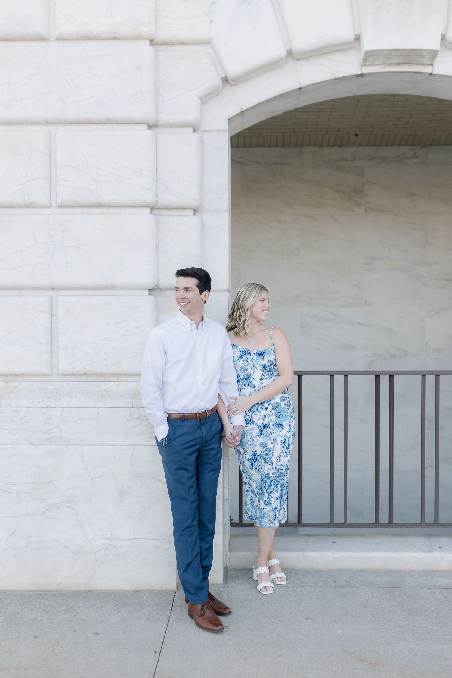 A couple stands by a white stone archway, with the woman wearing a blue floral dress and the man in a white shirt. Detroit Michigan Art Inst