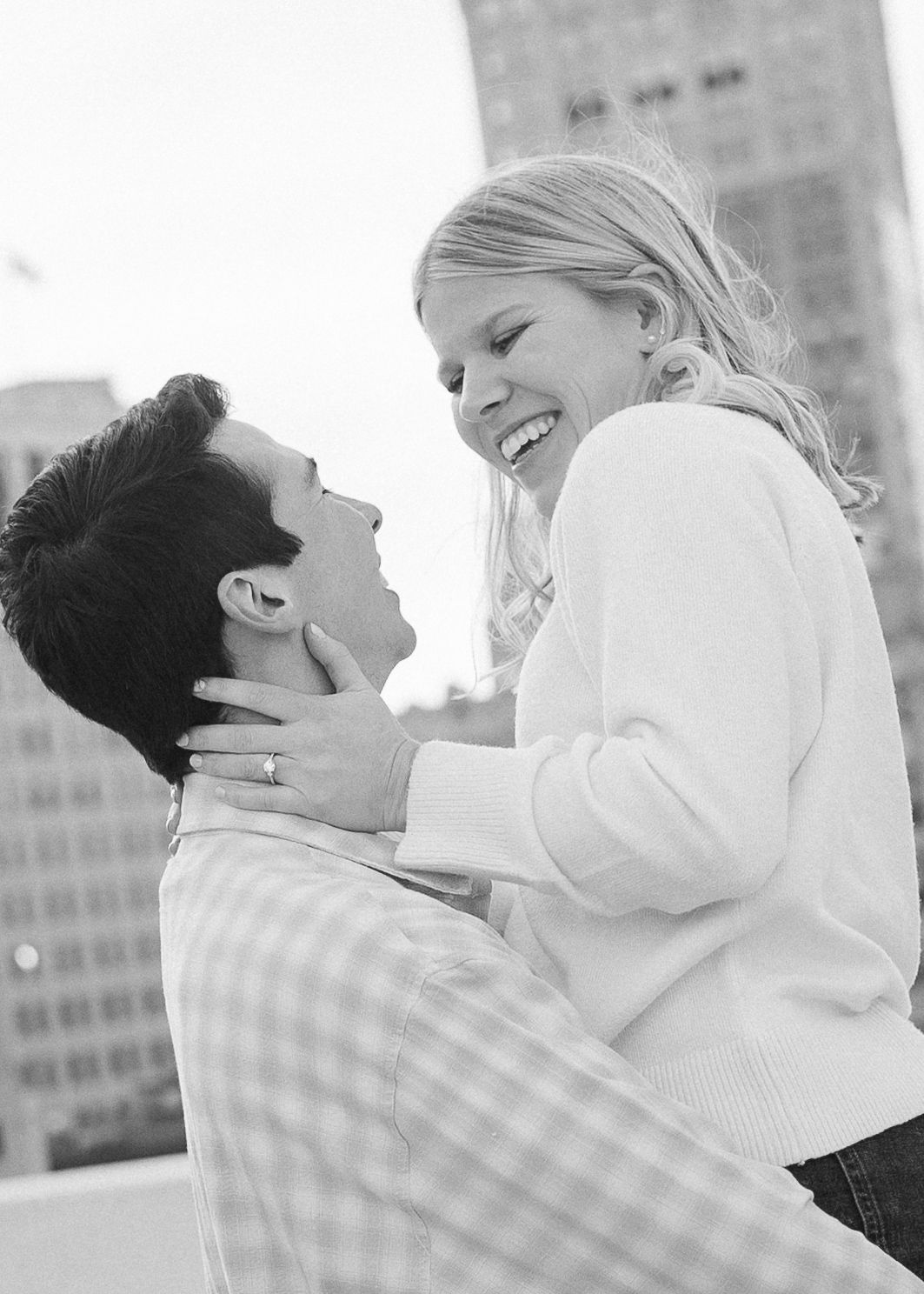 A joyful embrace captured in black and white against an urban backdrop.