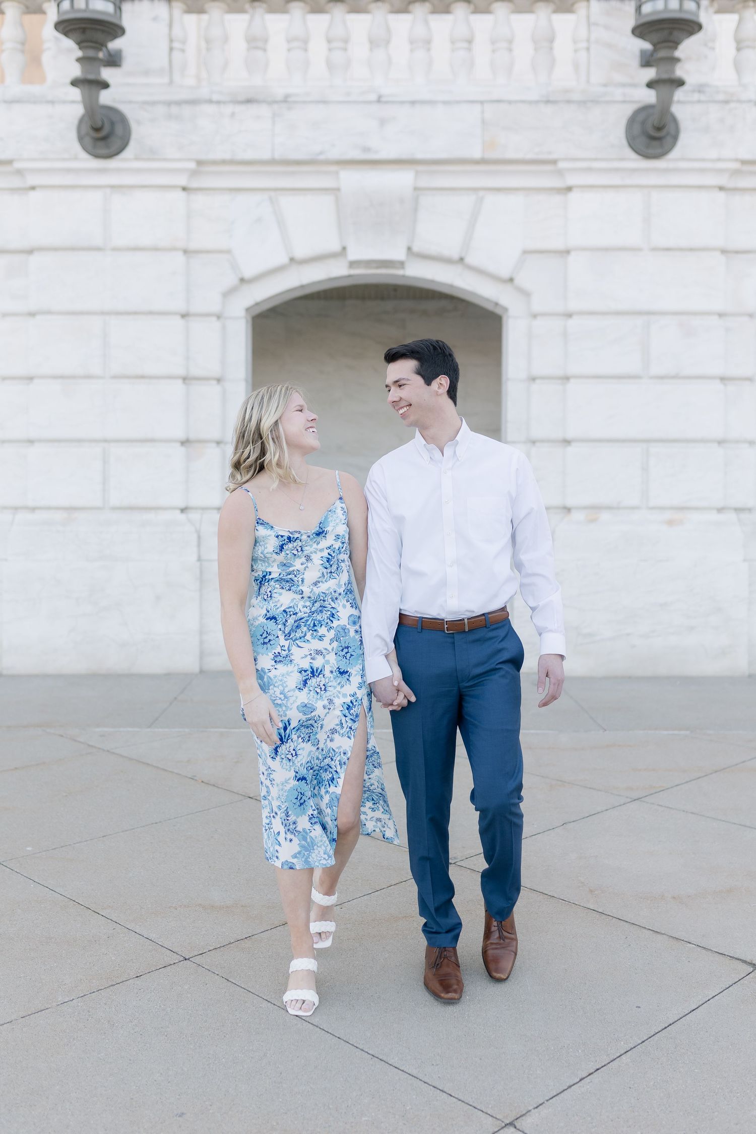 A romantic moment captured between two people walking along a white stone colonnade.